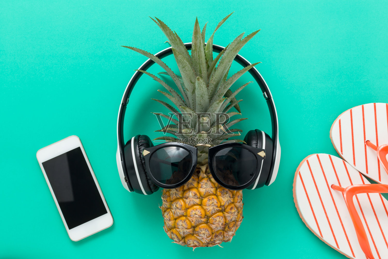 暑期假期背景概念，手机与菠萝，眼镜和人字拖在一个黄色的背景顶视图照片摄影图片