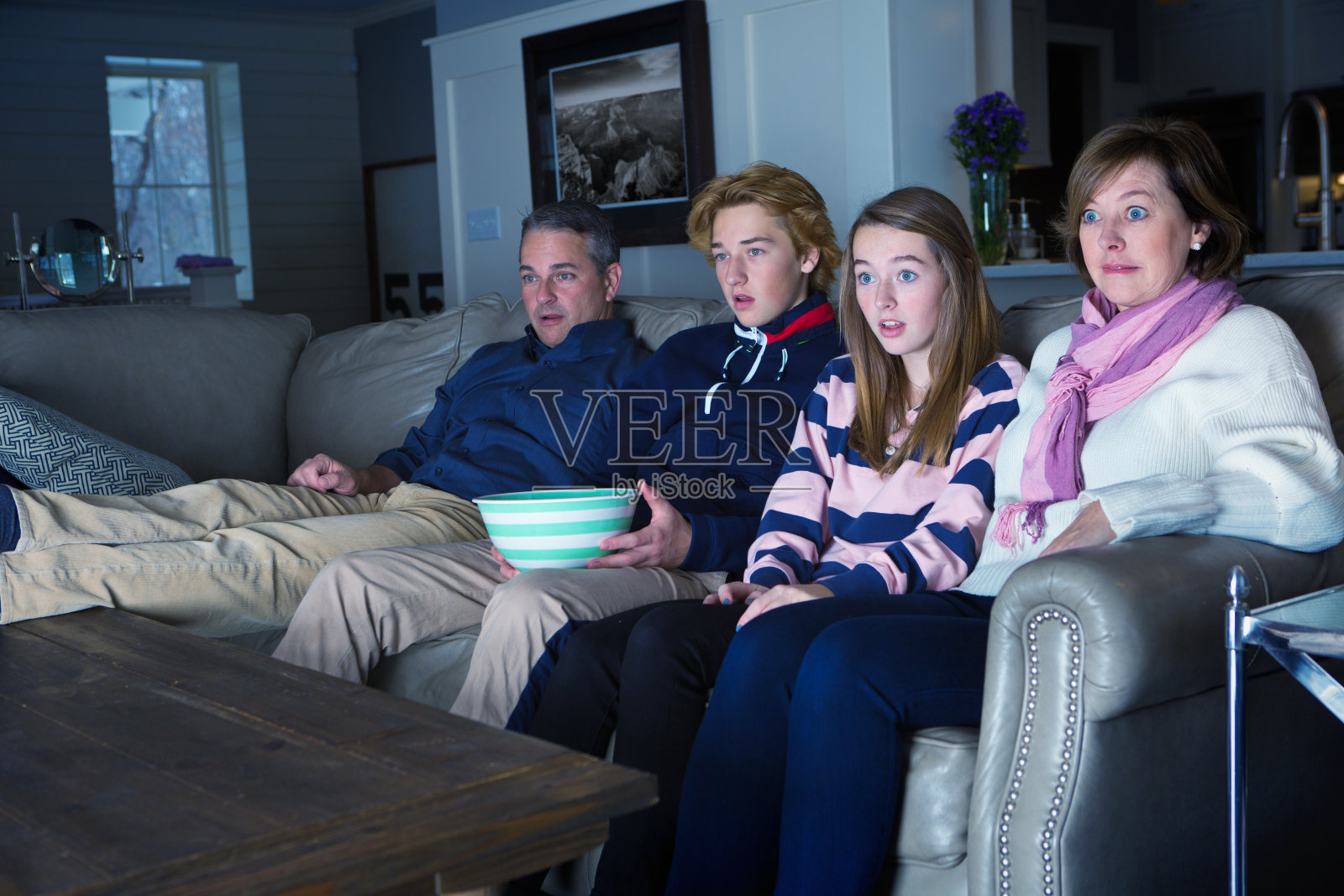 四口之家坐在一起看恐怖紧张的电视照片摄影图片
