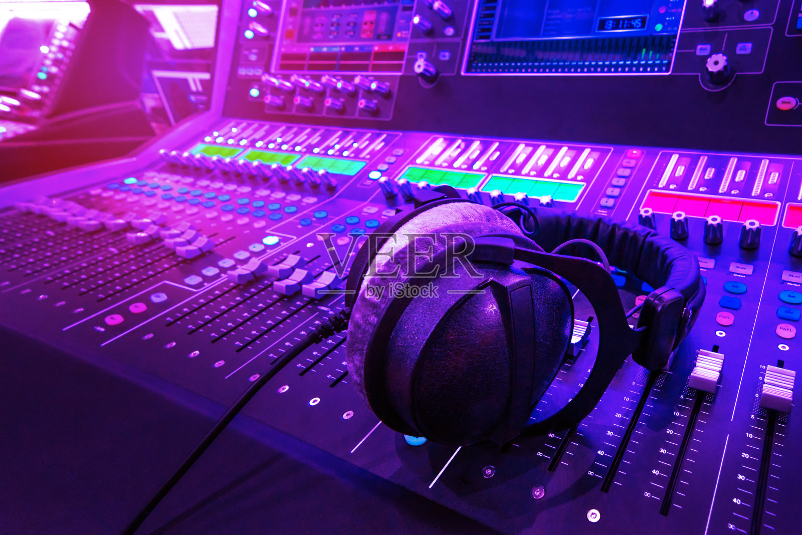 专业的录音室混音控制台面板，配有录音、调频器和调节旋钮，电视设备。蓝色和红色色调和近景图像与耀斑光效果。照片摄影图片