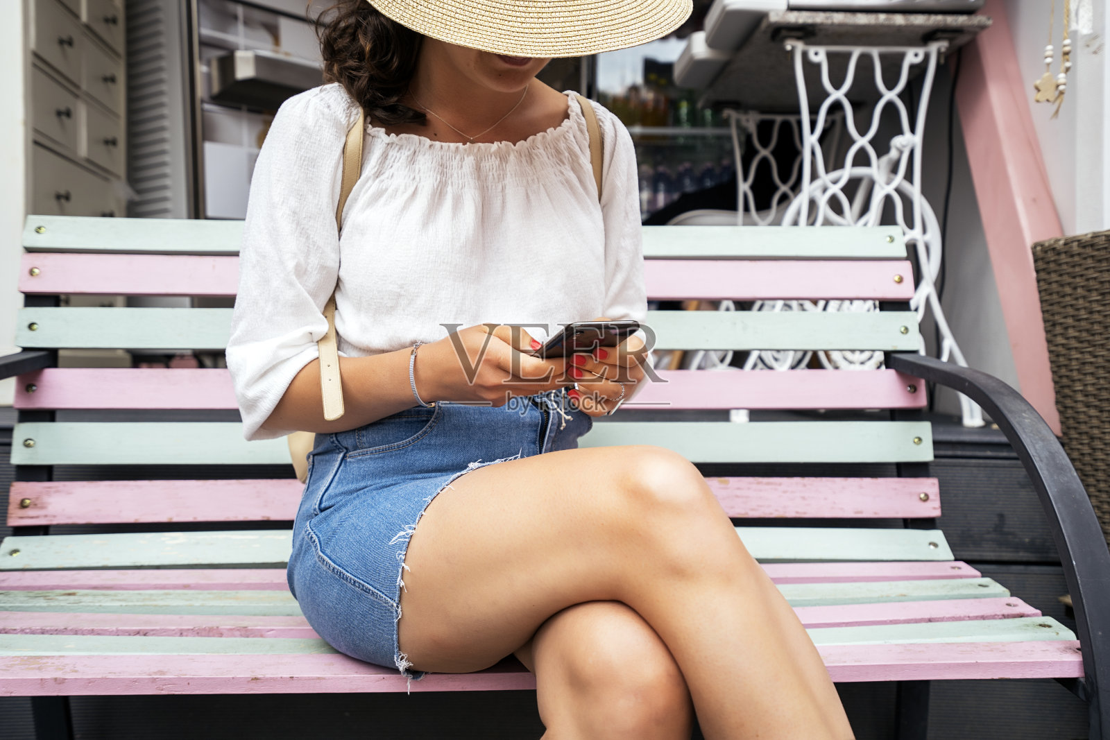 坐在街上用智能手机的帽子女人照片摄影图片