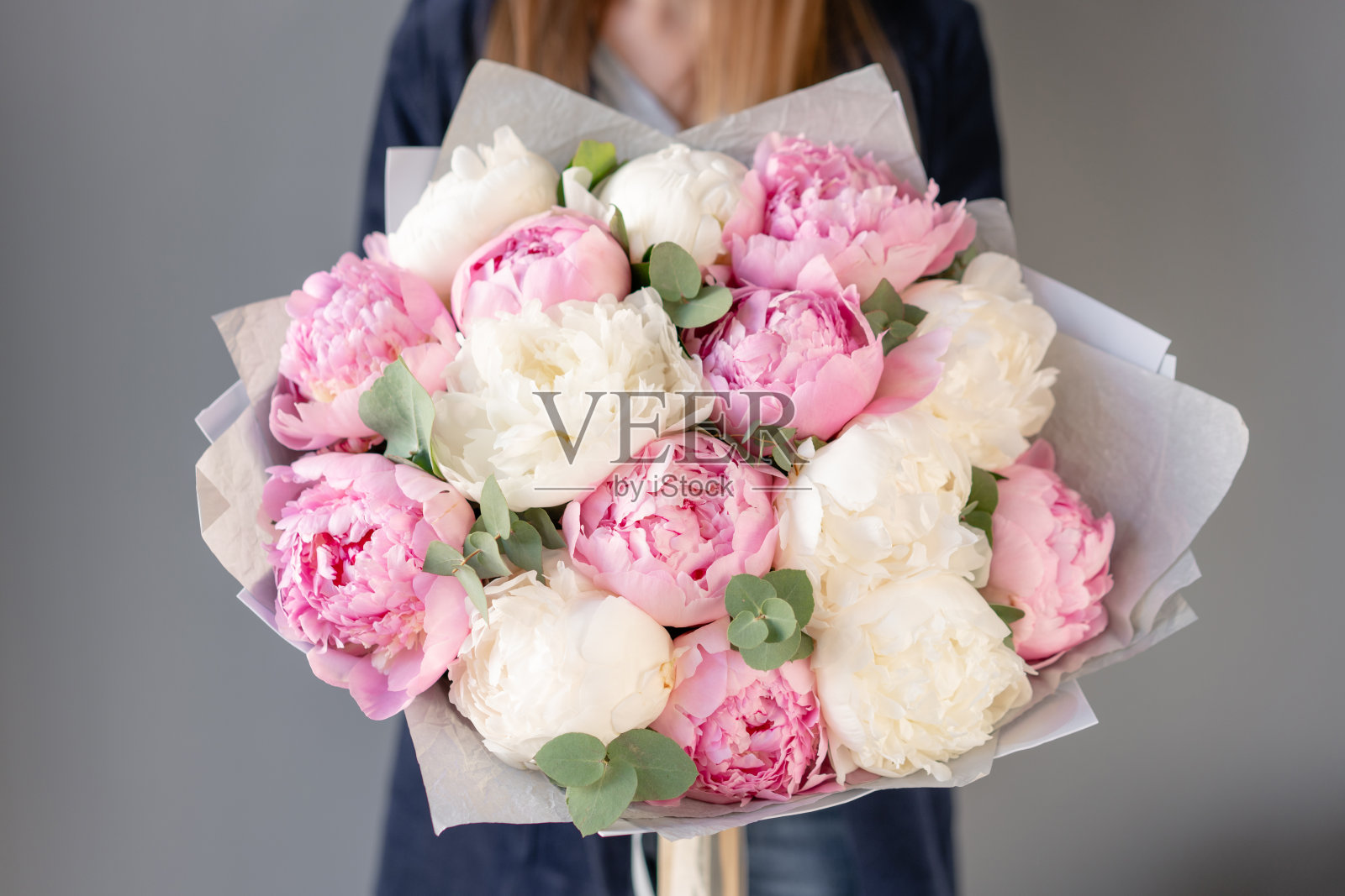 女人手里拿着粉白相间的牡丹。美丽的牡丹花为目录或网上商店。花店概念。漂亮的新鲜花束。鲜花交付照片摄影图片