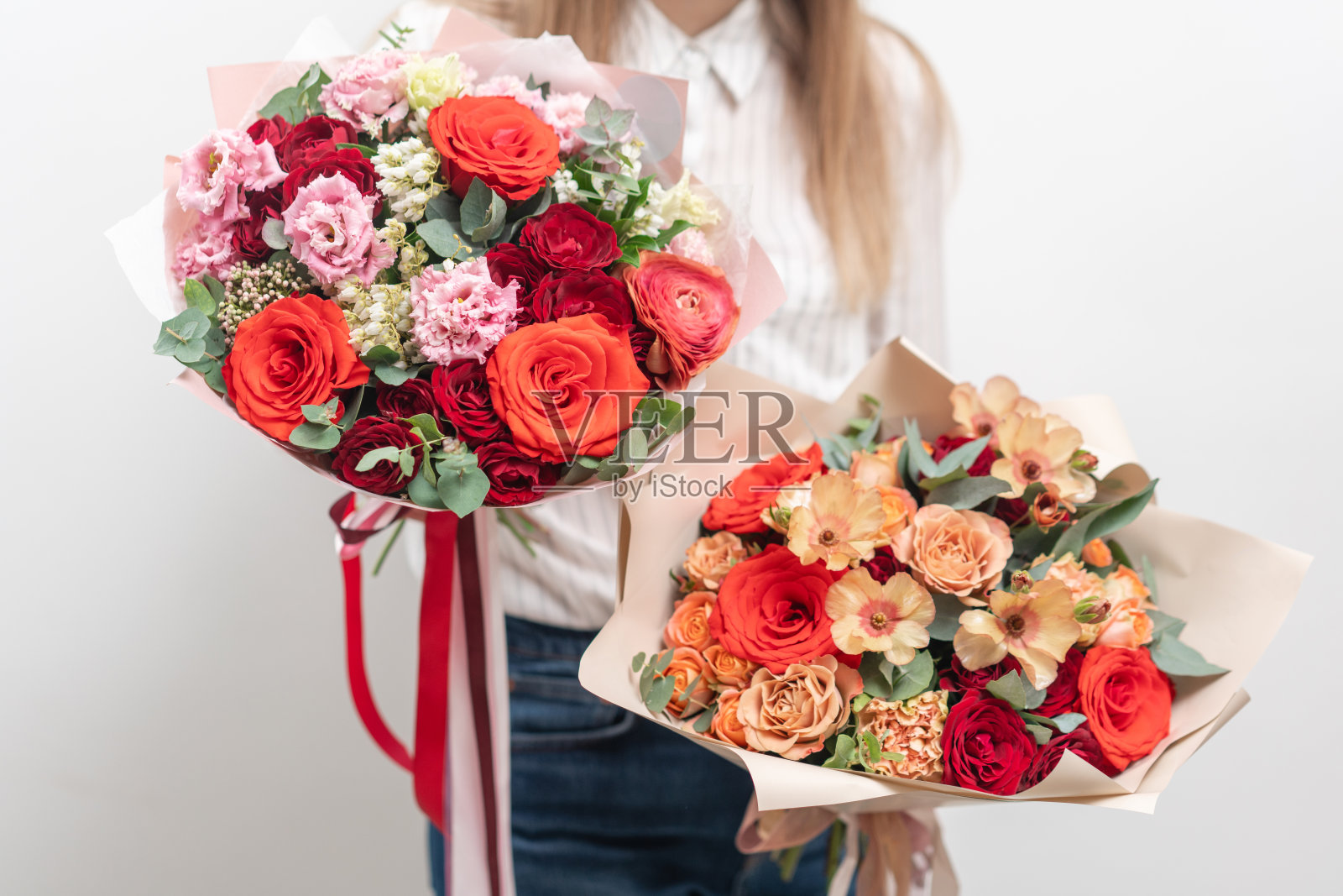 女人手里拿着两束美丽的混合鲜花。花店花匠的工作。精致柔和的颜色。新鲜切花。红色和桃红色照片摄影图片