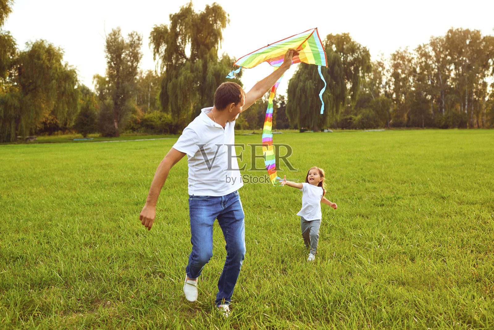 快乐的家庭，爸爸和孩子在草地上放风筝，在夏日的大自然中奔跑照片摄影图片