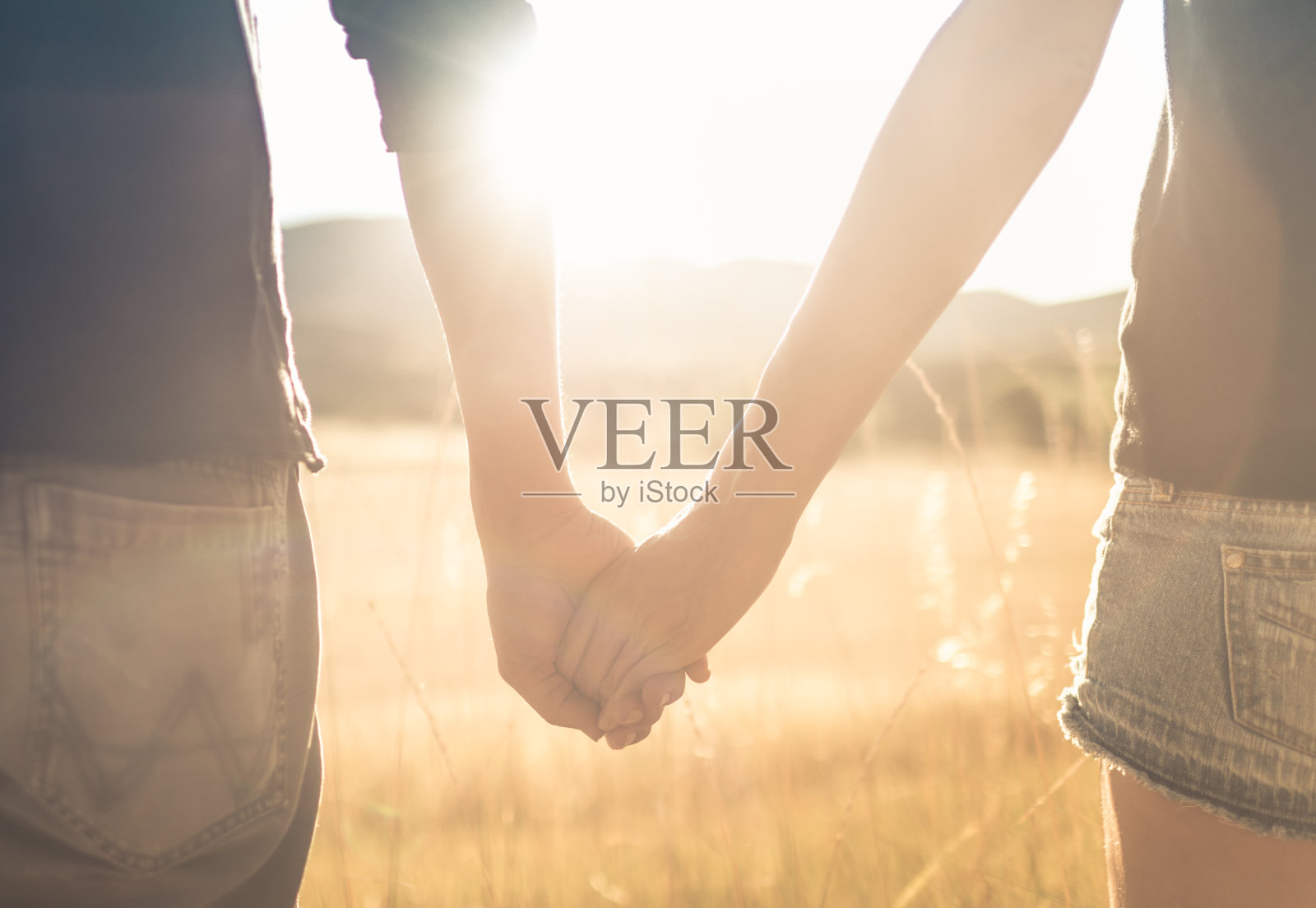 日落时分，一对年轻的夫妇牵着手。照片摄影图片