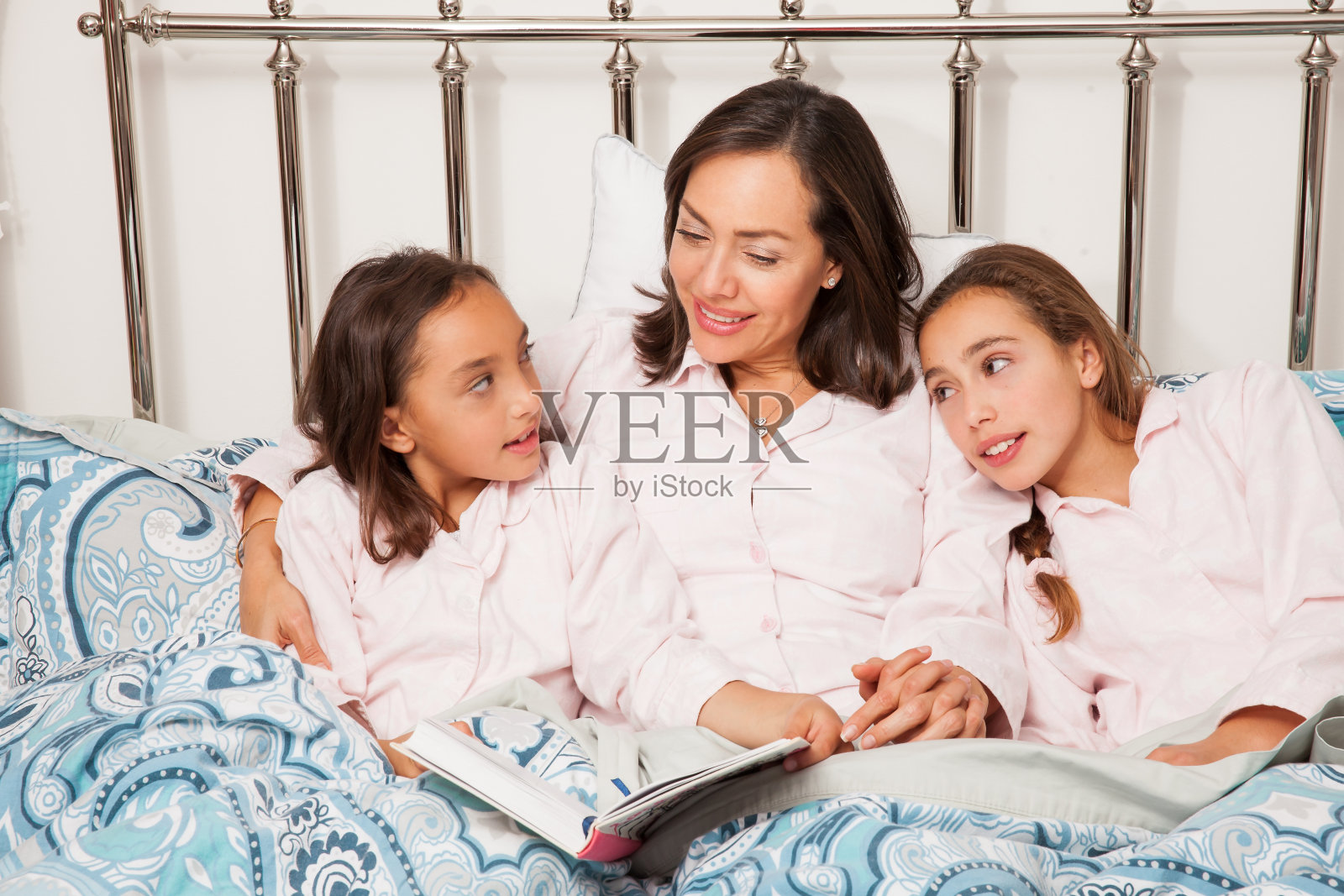 妈妈和她的两个女儿在睡前看书。真正的家庭照片摄影图片
