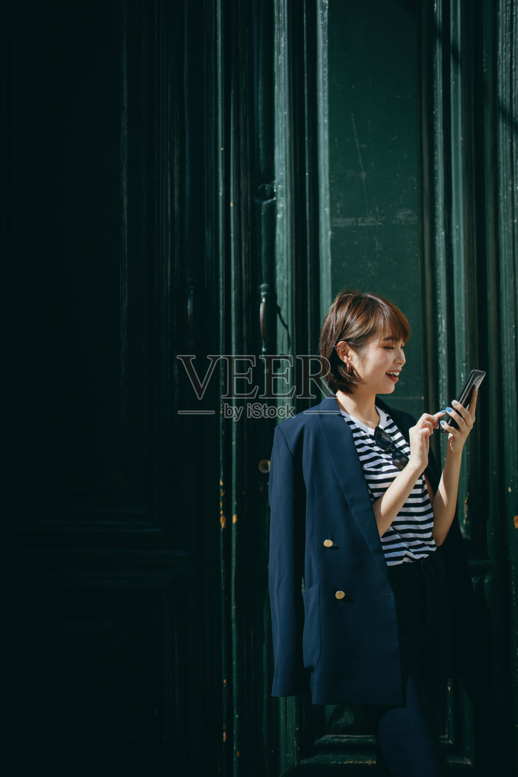 微笑的年轻亚洲女性使用智能手机在城市，在当地旅游景点前旅行照片摄影图片