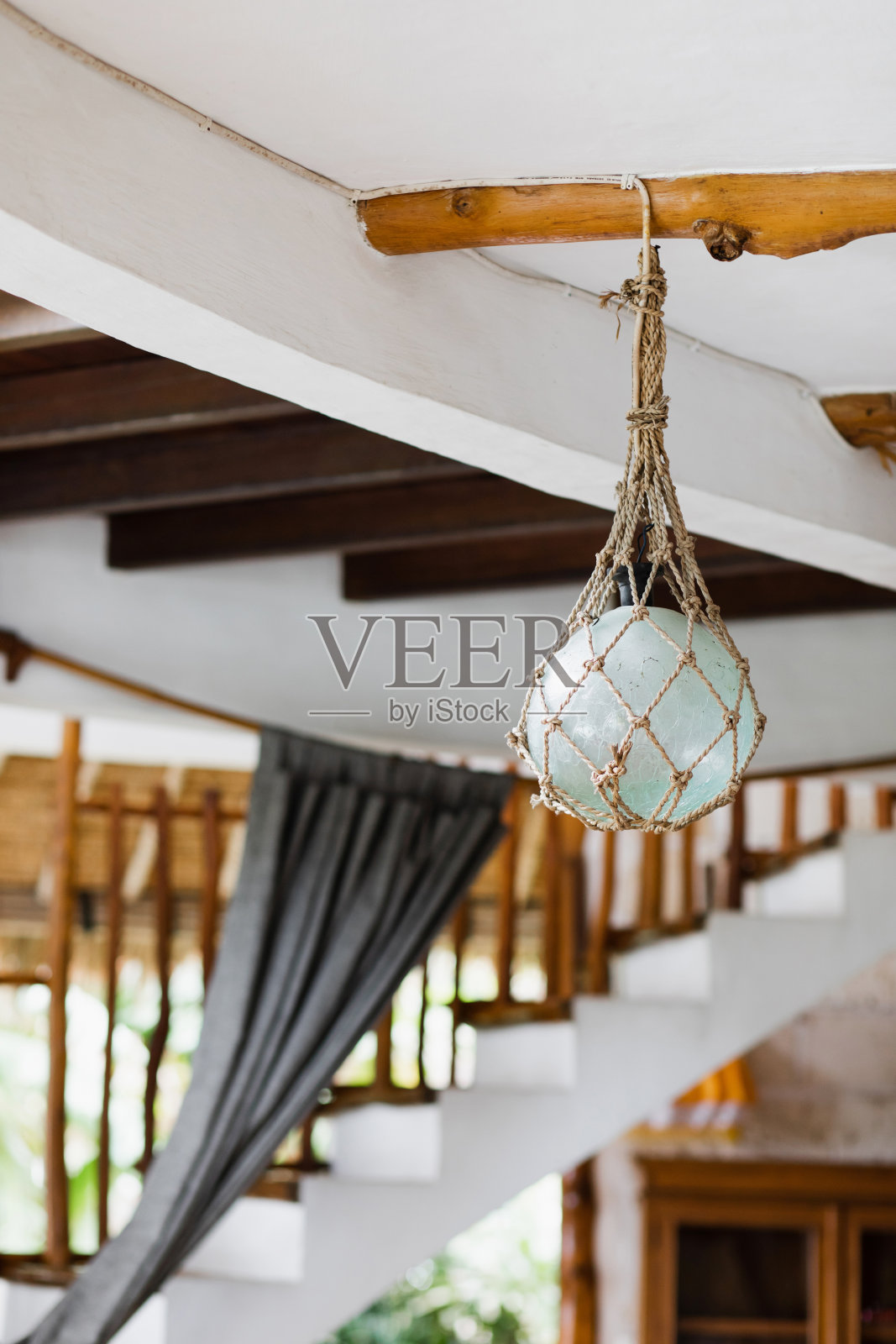 环保风格的室内设计元素。用工艺绳索包裹的玻璃灯悬挂在木质屋顶上。在巴厘岛别墅。照片摄影图片