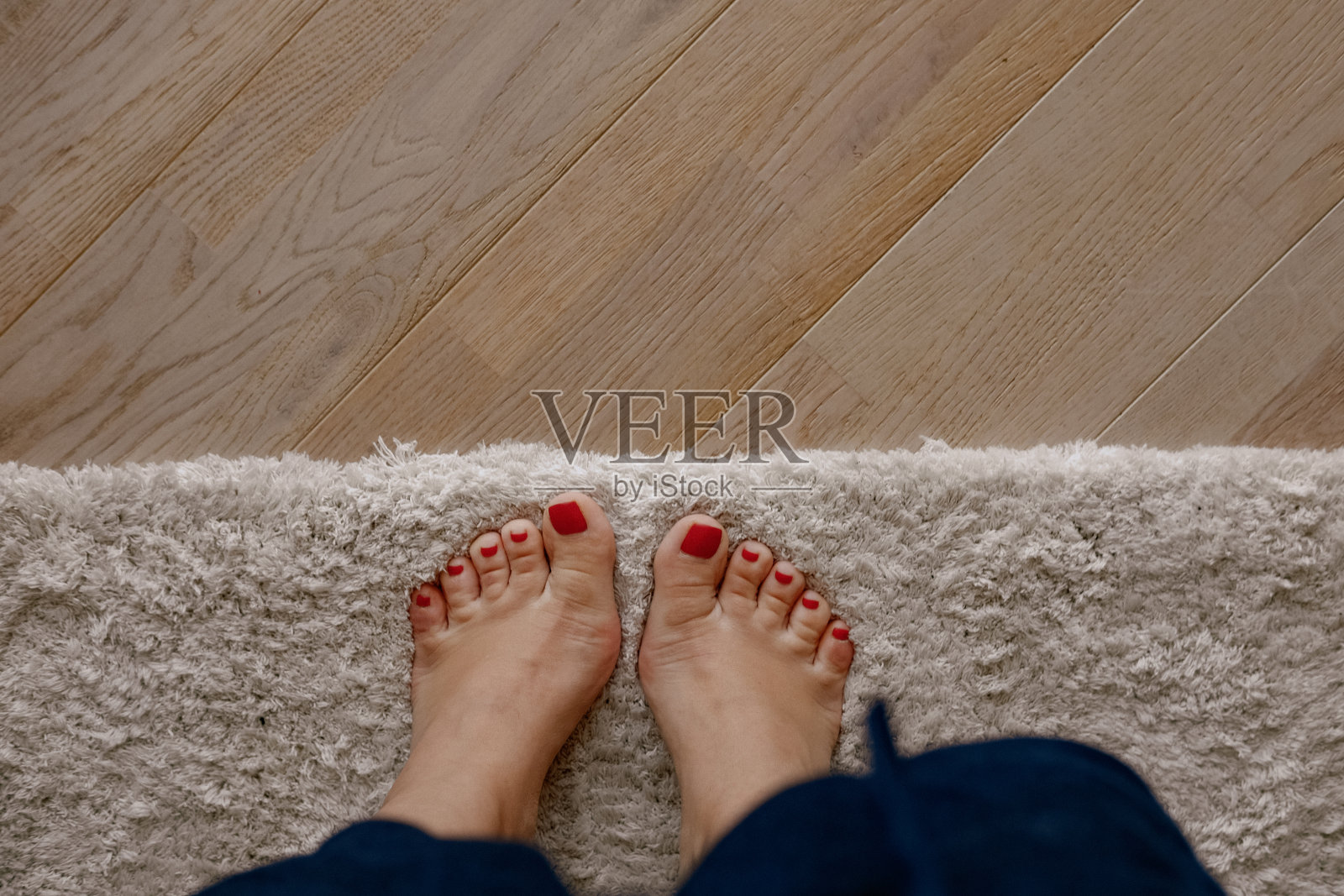 女人的脚踩在地毯和木质地板上照片摄影图片