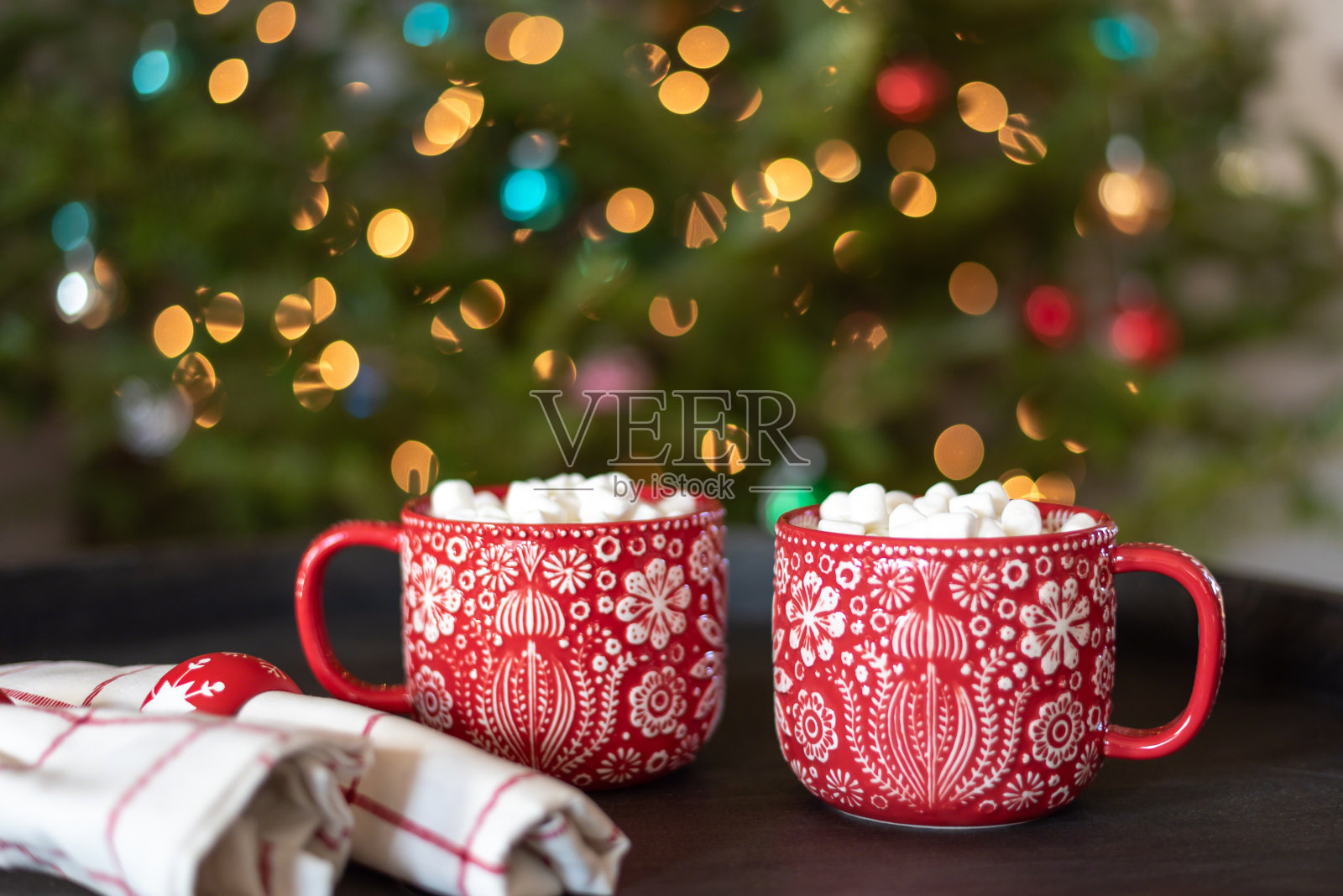 在圣诞树前喝两杯热巧克力照片摄影图片