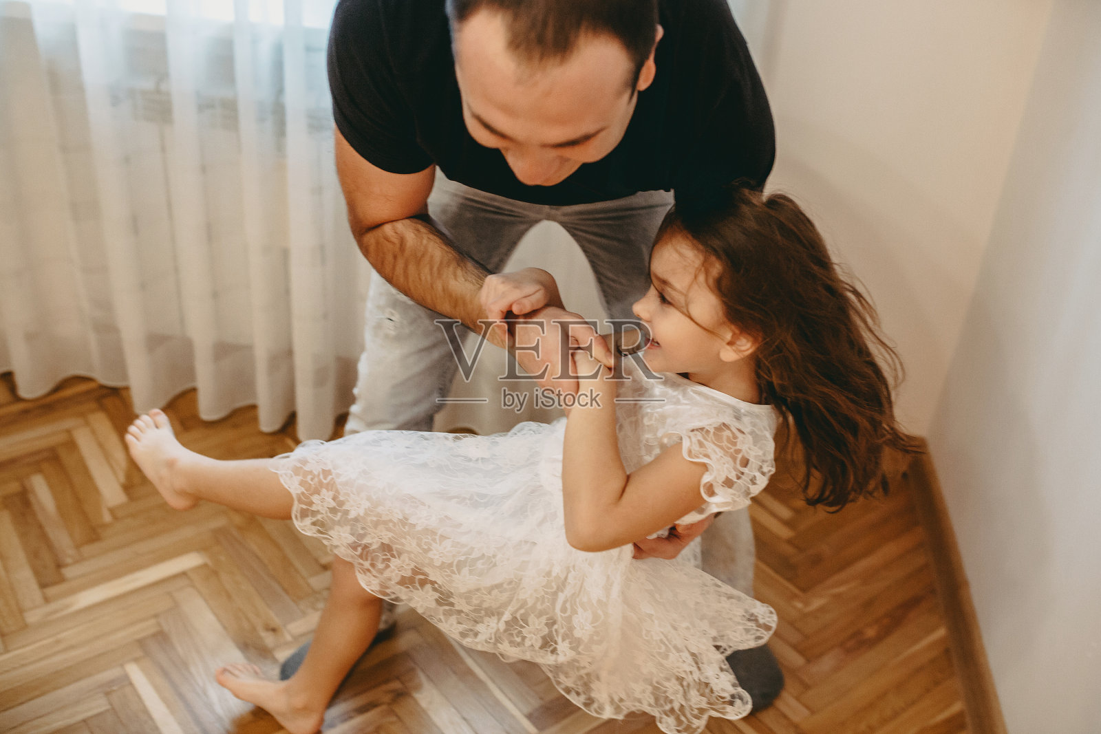 可爱的小女孩和她的父亲在家里跳舞在早上笑。照片摄影图片