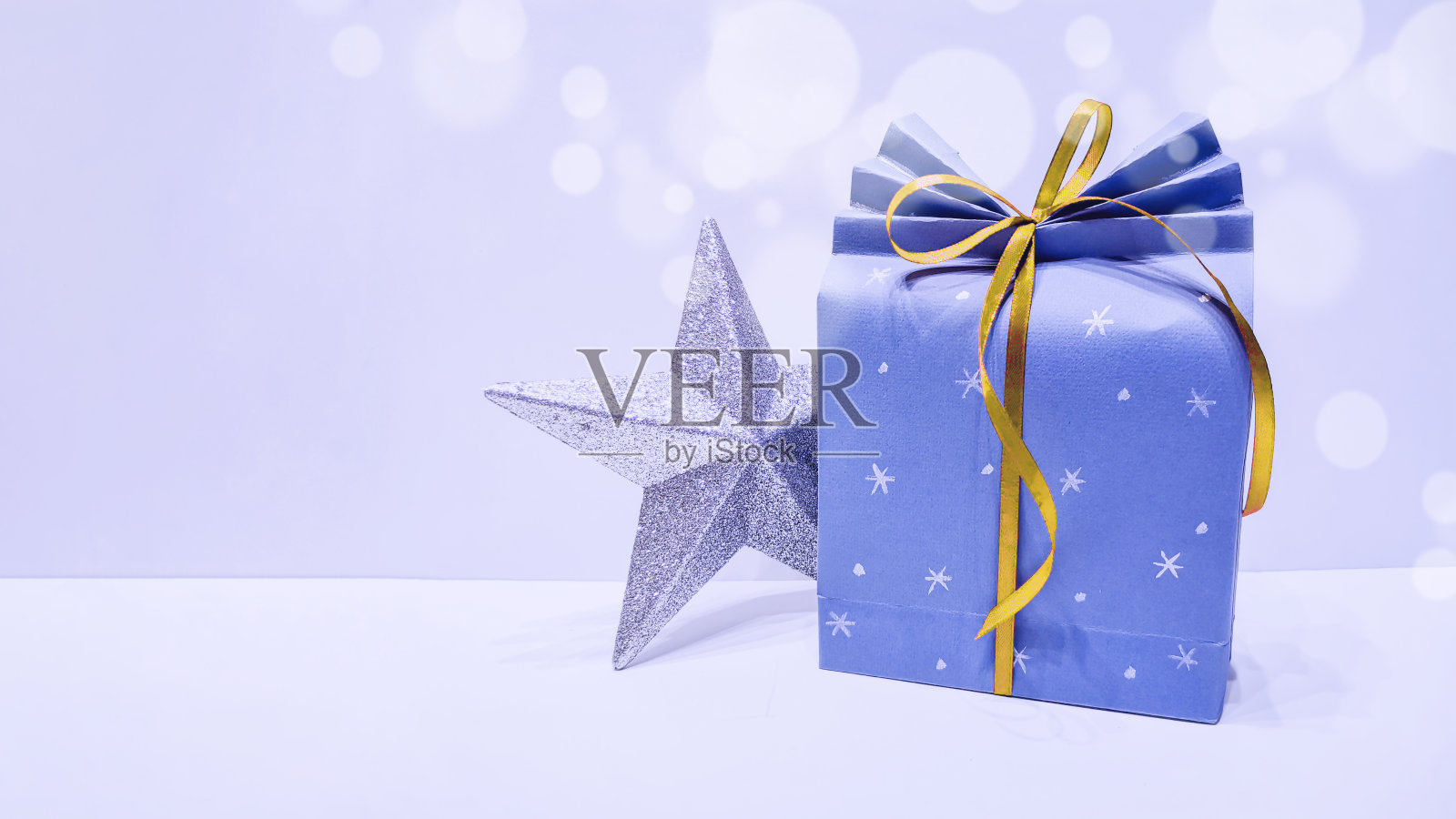 圣诞闪亮的星星和可爱的带黄色丝带的蓝色礼品袋。新年和圣诞节概念，2020年流行蓝色经典色调。照片摄影图片