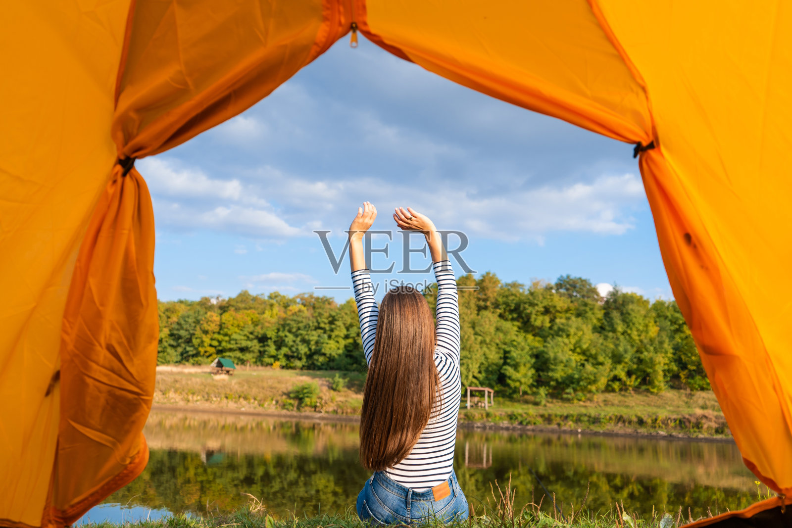 日落时分，在湖边露营，从游客帐篷内观看。女孩在帐篷前享受大自然照片摄影图片