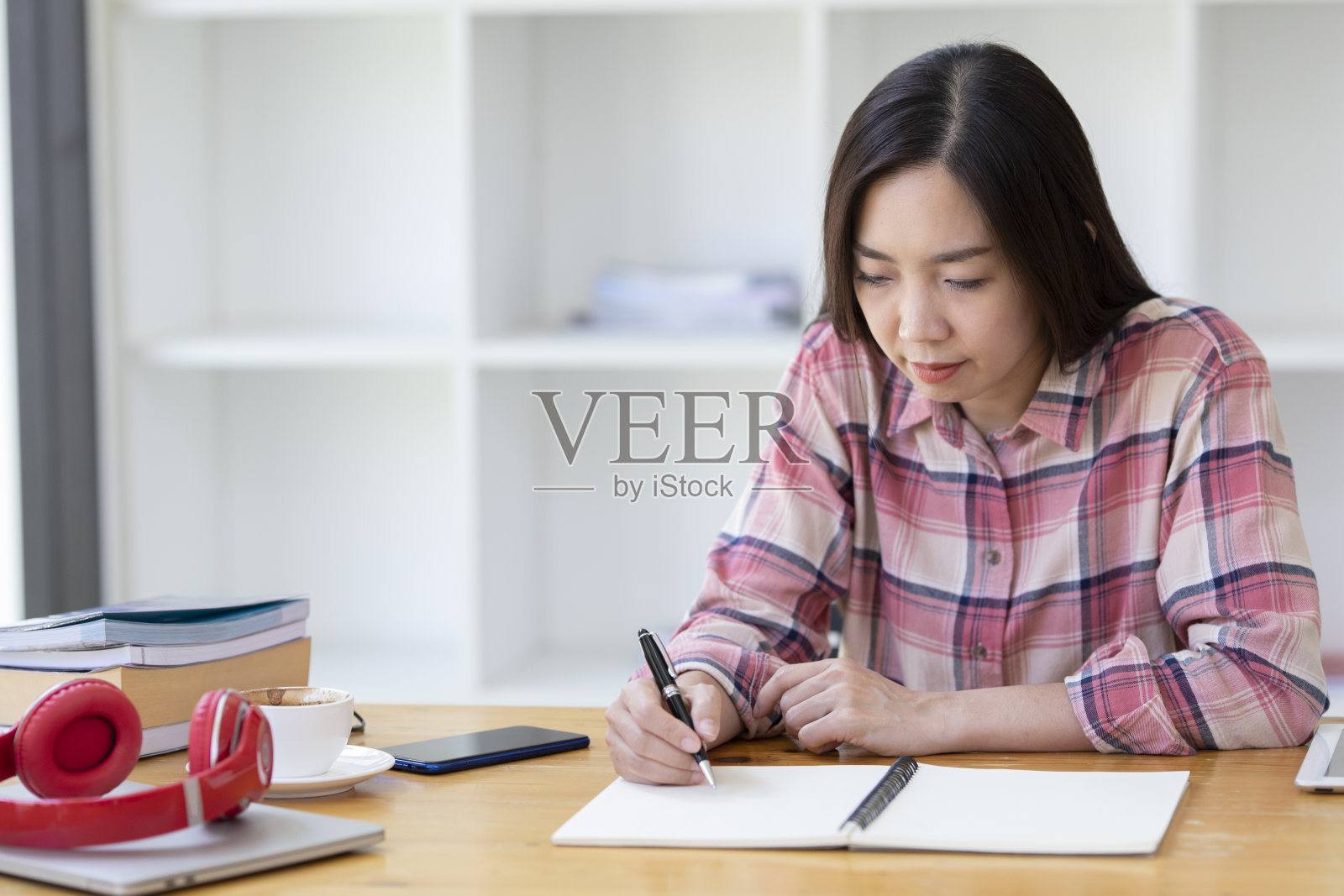 一个亚洲女人在笔记本上写东西。商业女性在纸上手写一些东西。照片摄影图片