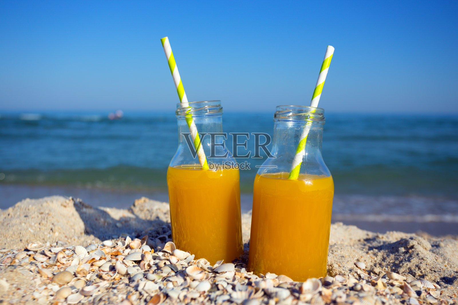 新鲜橙汁。两瓶橙汁，用吸管放在海里。夏天剩下“n照片摄影图片
