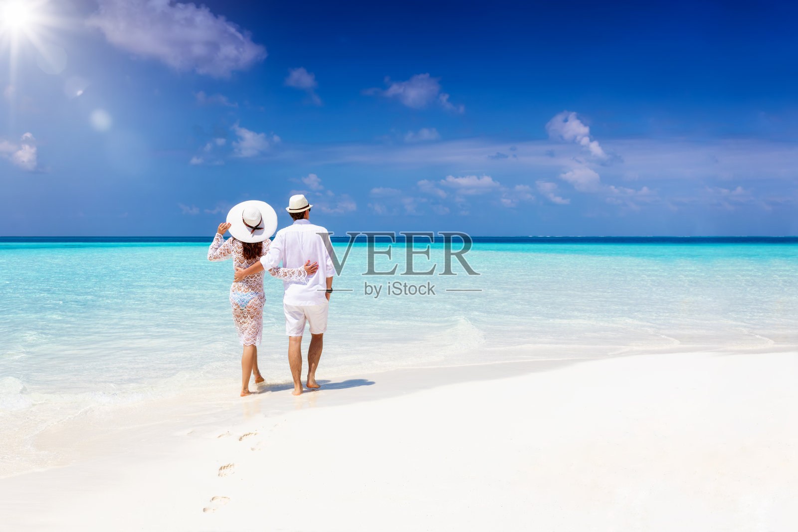 一对情侣在度假期间拥抱着走在热带海滩上照片摄影图片