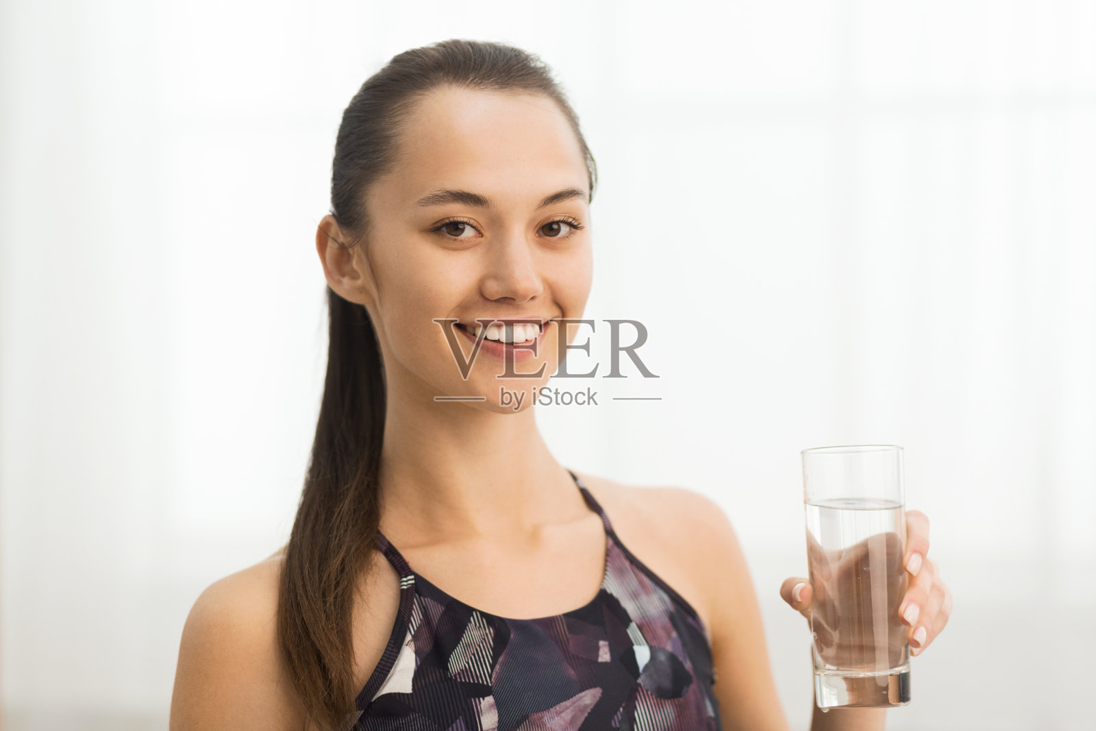 水合作用的概念。在家锻炼后喝杯水的女孩照片摄影图片