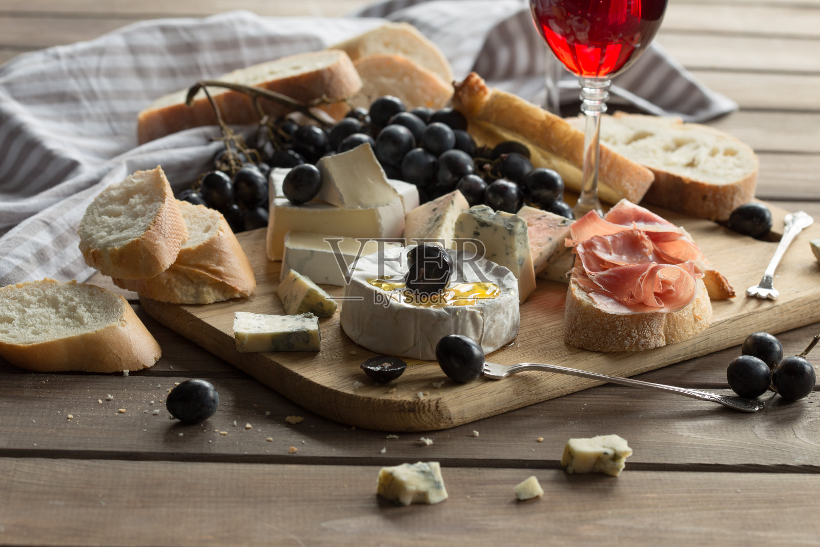 什锦奶酪放在木板上。卡门贝尔奶酪，蓝霉奶酪，豪达干酪，硬奶酪，葡萄，红酒照片摄影图片