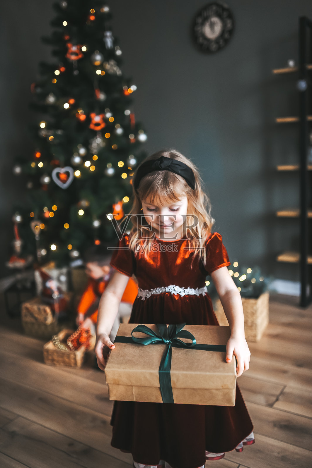 小女孩躲在一个大礼品盒后面。活泼可爱的小女孩与礼物。照片摄影图片