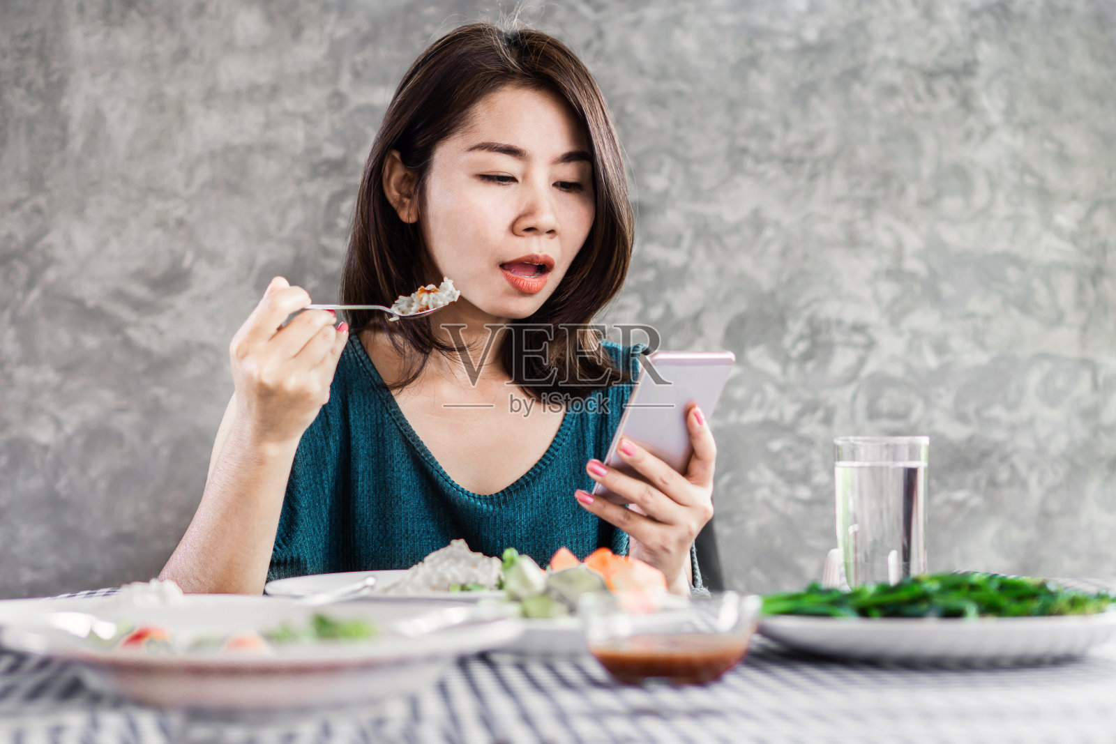 亚洲女性在家里吃饭时使用手机，上网，沉迷社交媒体的概念照片摄影图片
