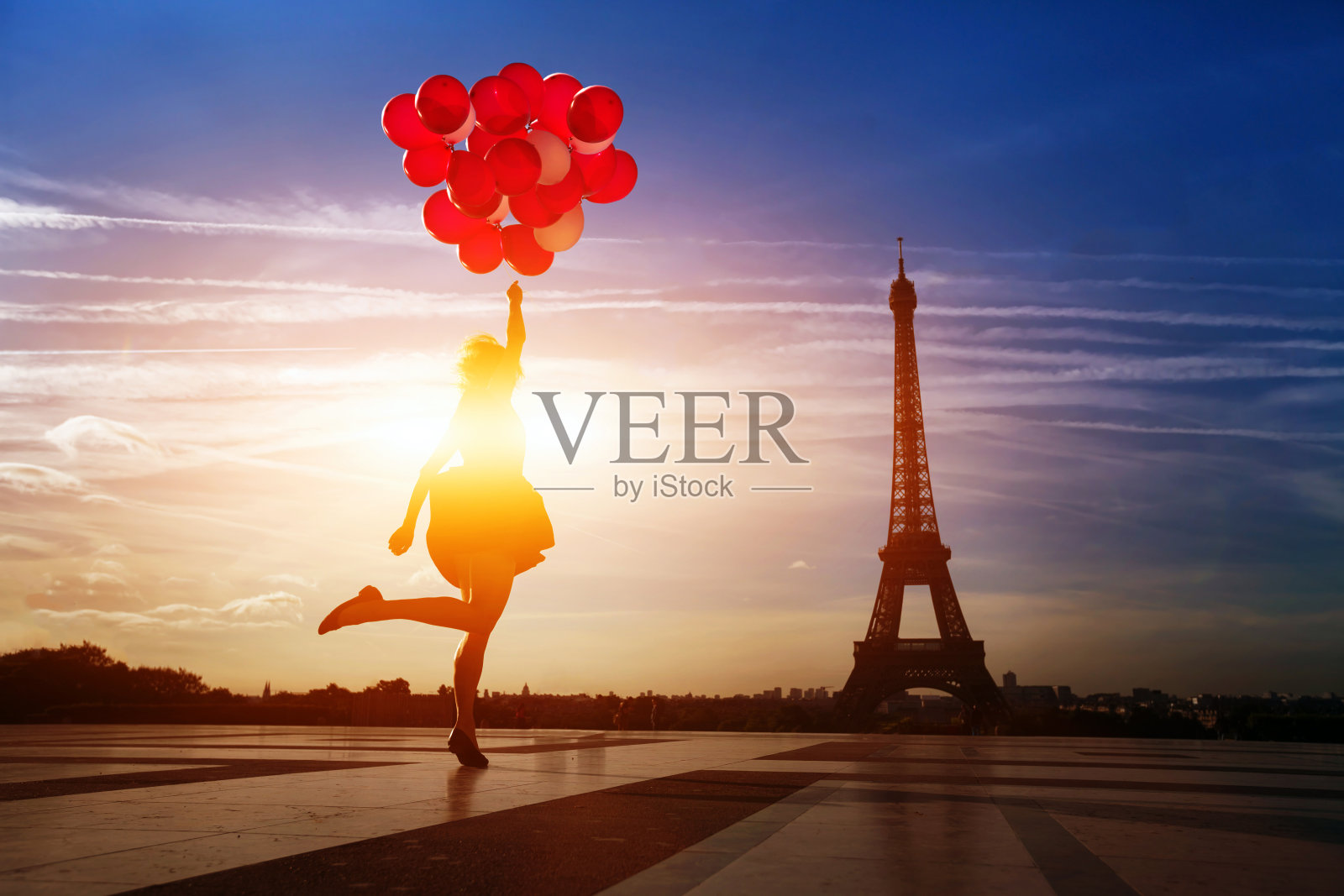 一个拿着红气球的女人在巴黎埃菲尔铁塔附近跳照片摄影图片