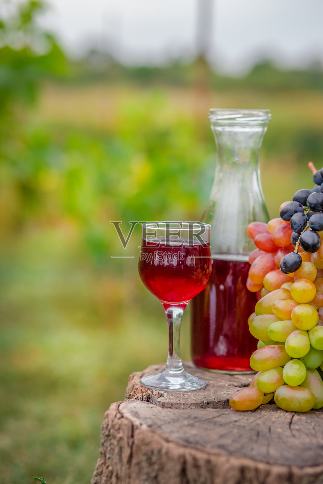 有机水果篮在夏季草。醒酒器和一杯葡萄酒。照片摄影图片