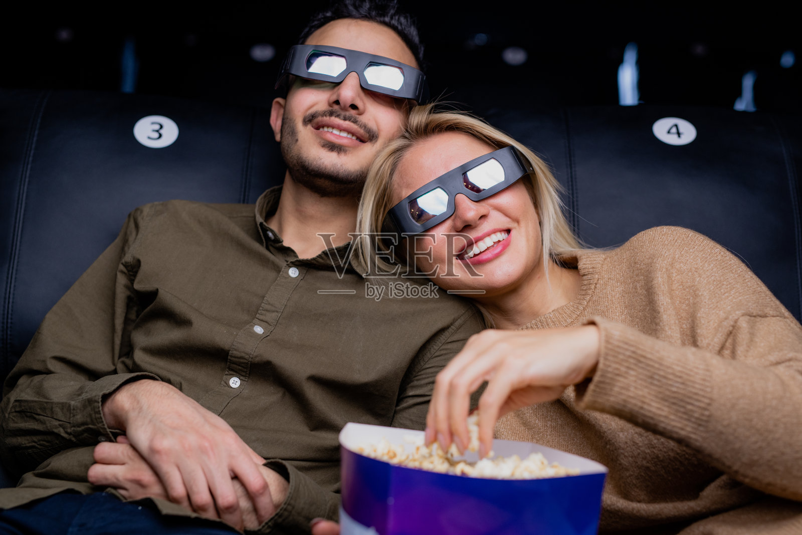 幸福的年轻多情夫妇在3d眼镜看有趣的动作片照片摄影图片