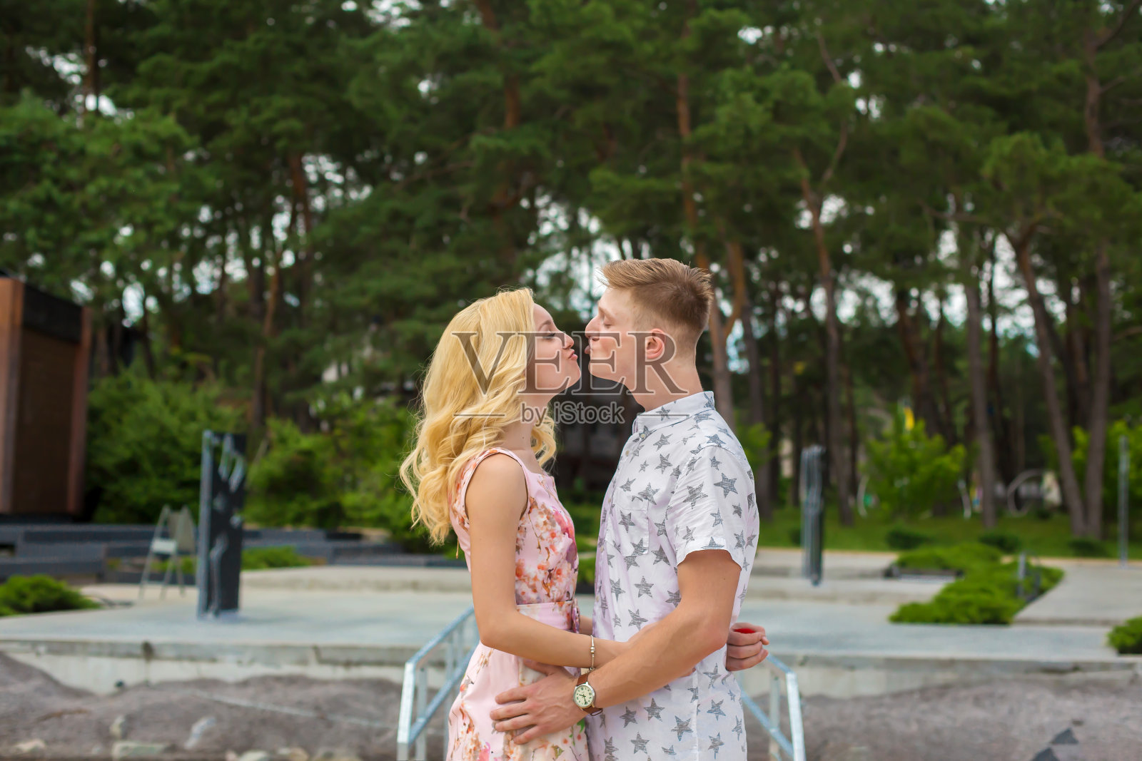 相爱的年轻夫妇亲吻在绿色的公园照片摄影图片