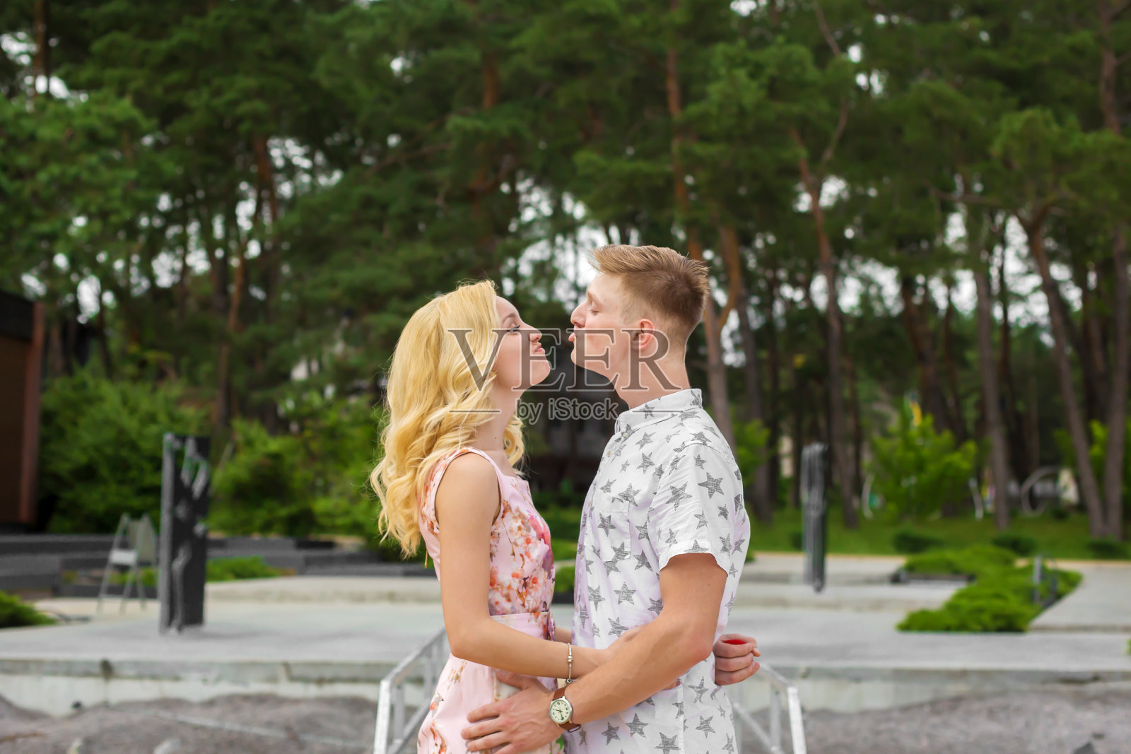 相爱的年轻夫妇亲吻在绿色的公园照片摄影图片