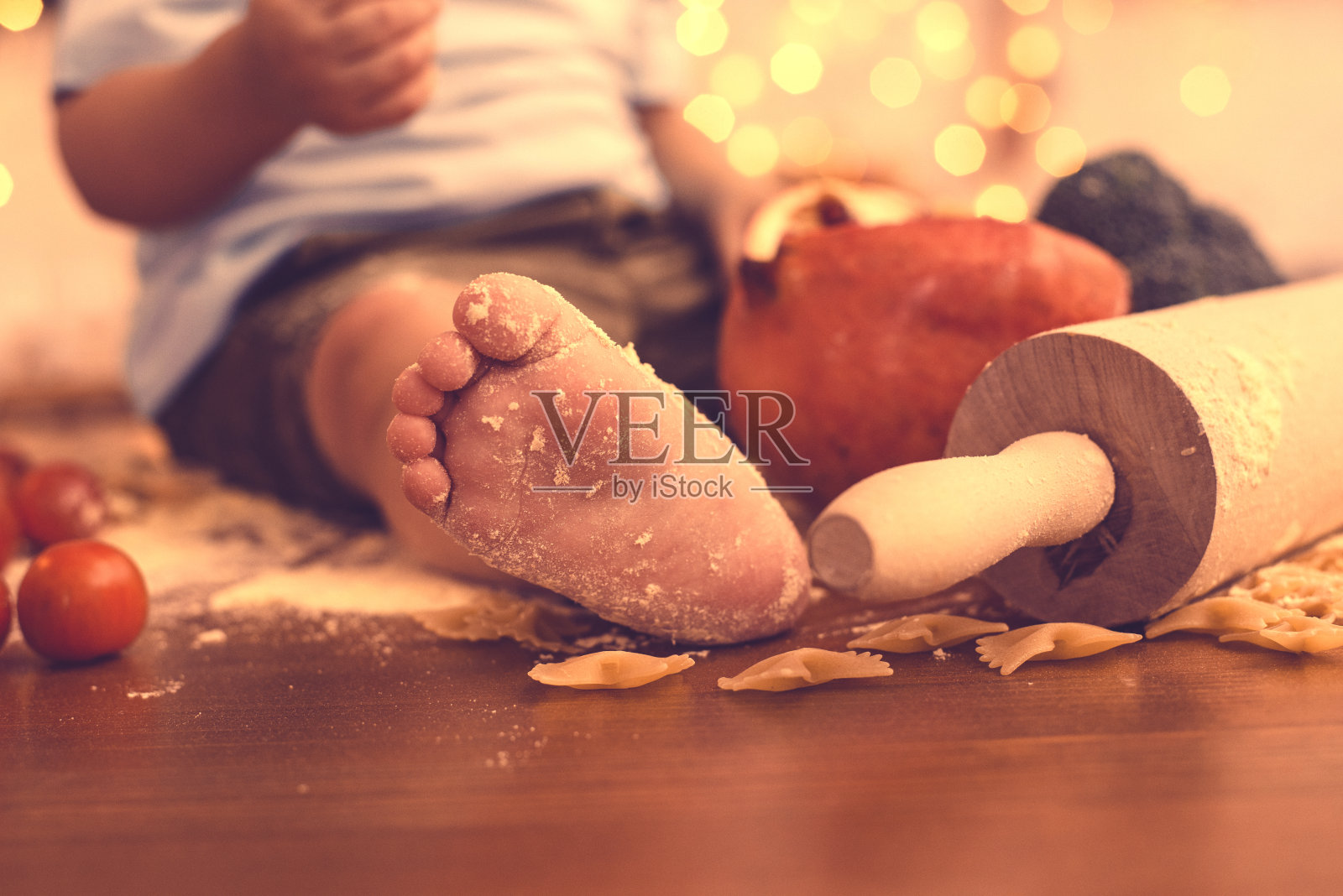 厨房里一个小孩的脚。婴儿食品的概念，关爱儿童及其营养。帮助一个孩子的妈妈做饭，意大利面和沙拉照片摄影图片