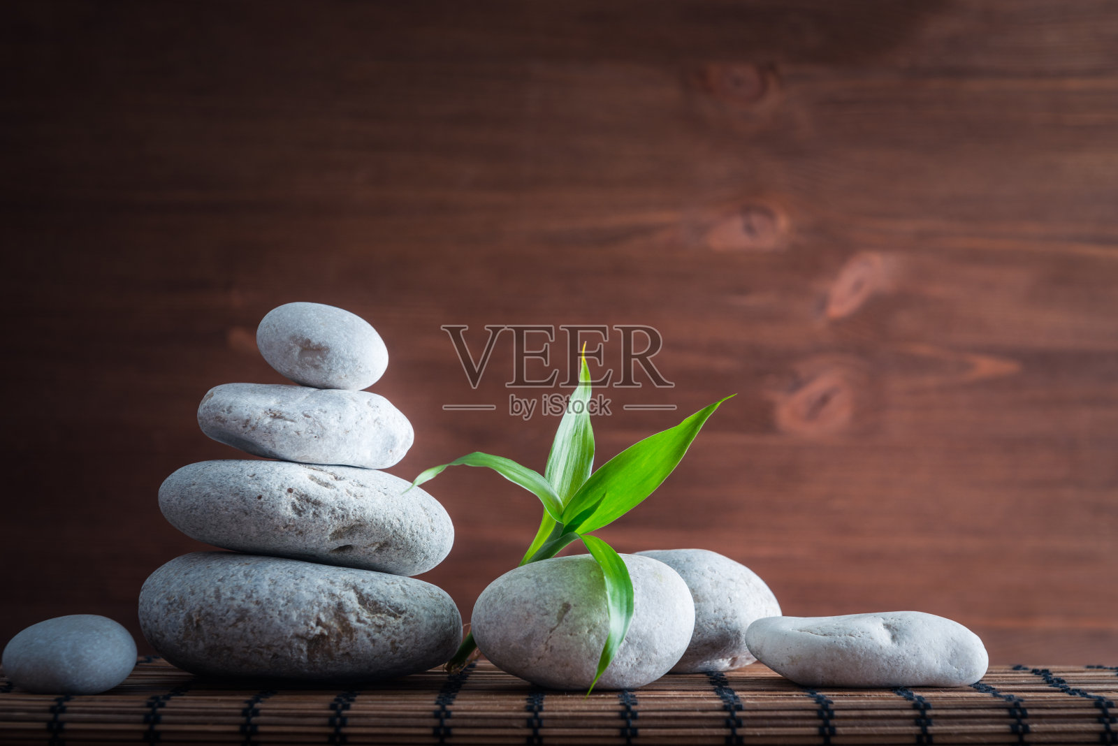 白色禅宗平衡石，竹木桌上的植物照片摄影图片