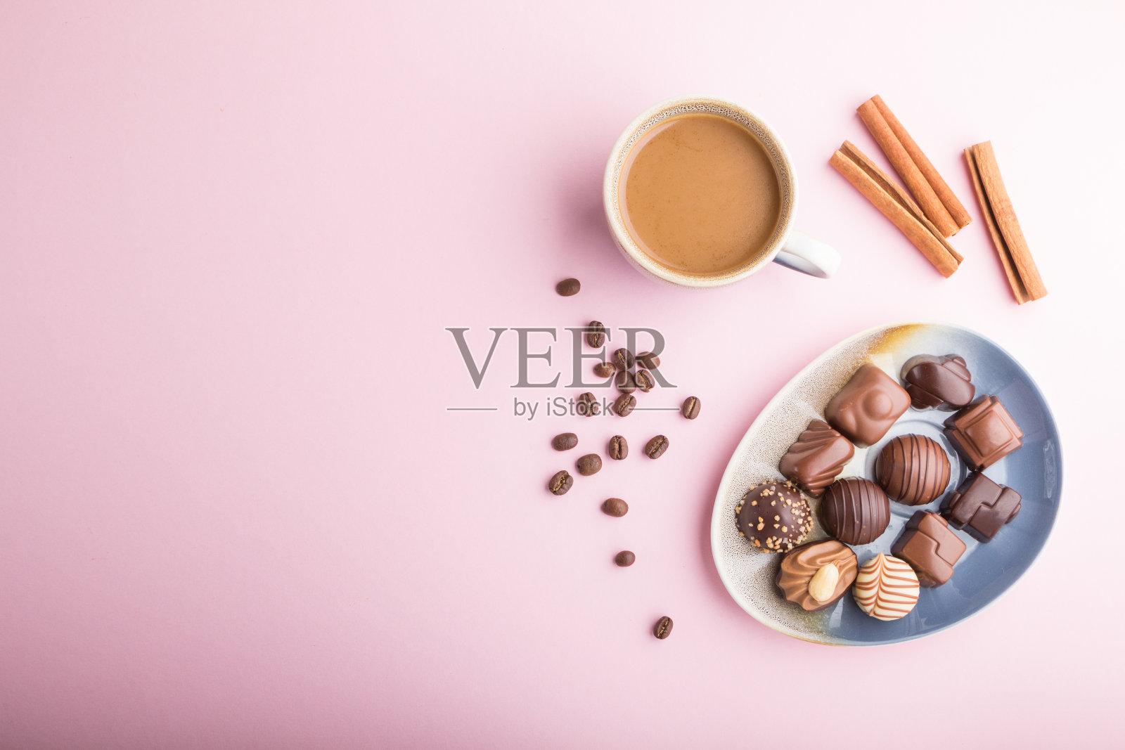 不同的巧克力糖果和一杯咖啡在粉红色的背景。俯视图，平放，复制空间。照片摄影图片