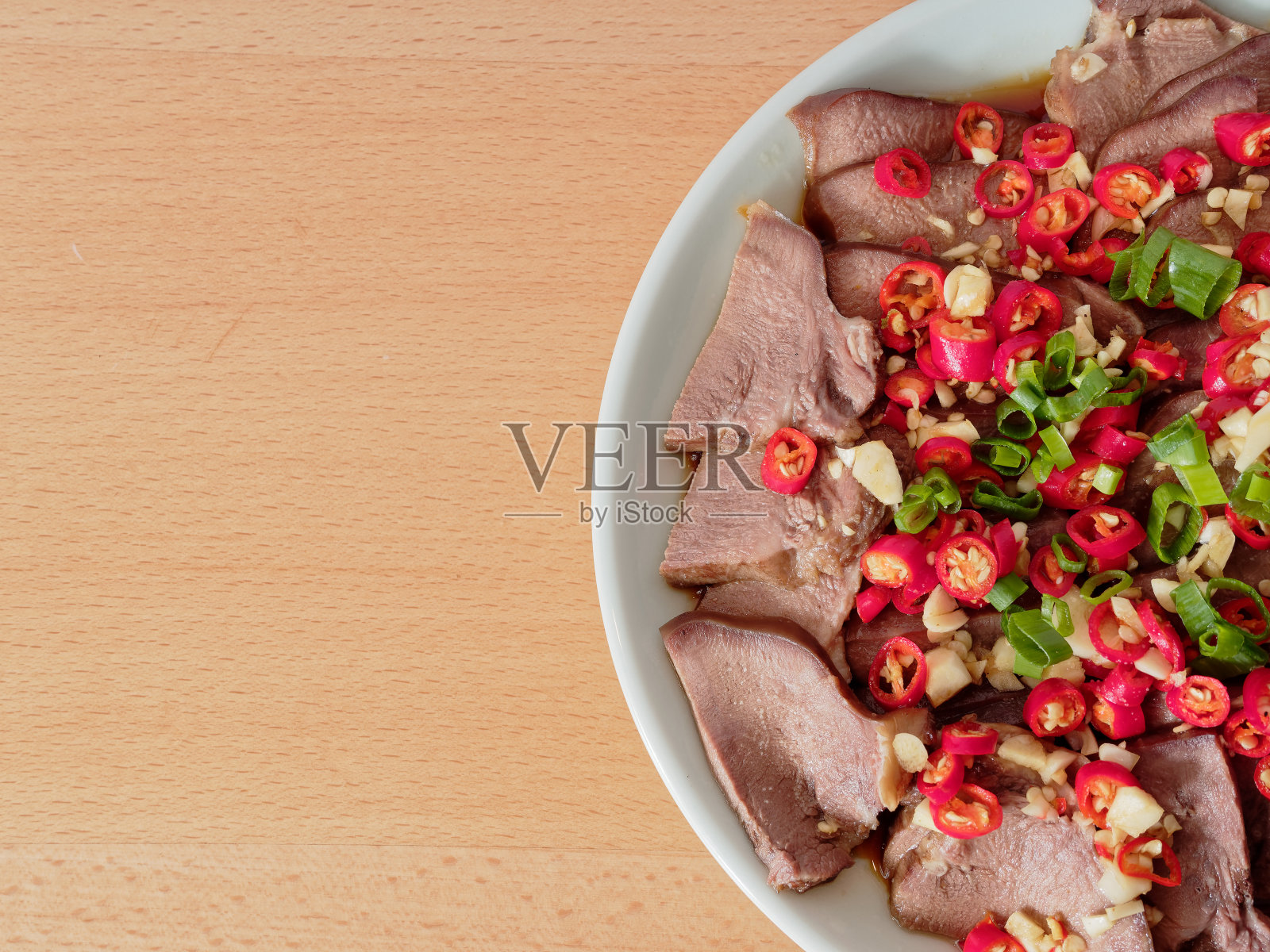 白盘子里的熟肉片配上红绿辣椒。美味的中国菜，左边有拷贝空间。照片摄影图片