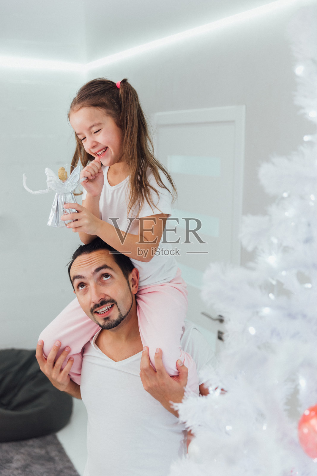 hristmas树装饰。的童年。首页小女孩坐在爸爸的脖子上玩圣诞树，两人都在微笑照片摄影图片