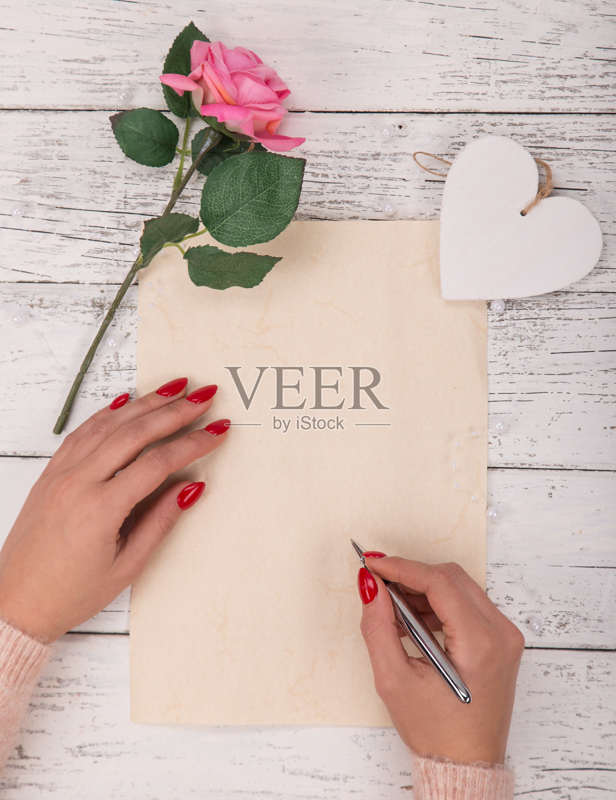 空的白纸和女人的手。背景与粉红玫瑰在花瓶。照片摄影图片