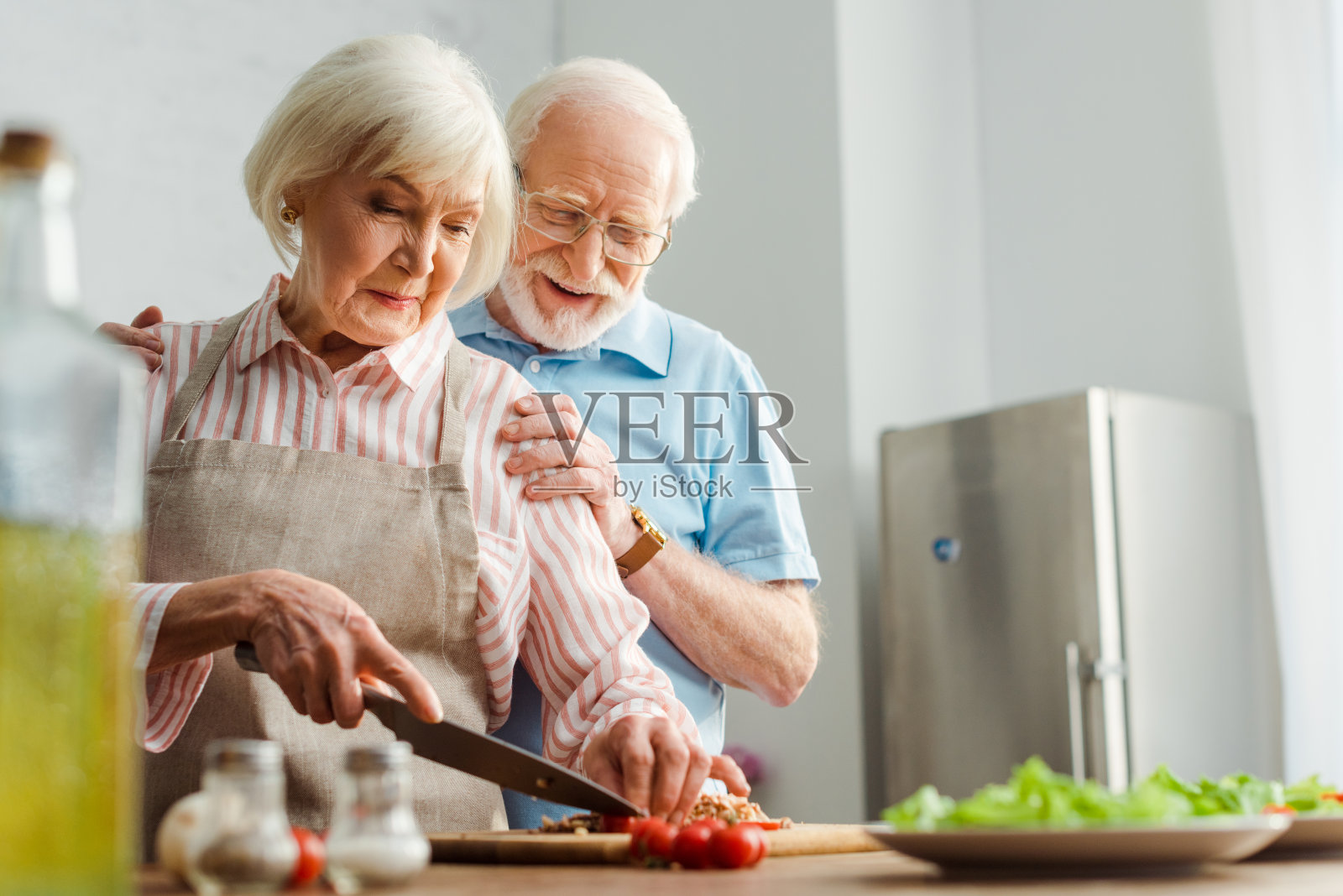 在餐桌上做饭时，有选择地关注老人微笑着拥抱妻子照片摄影图片