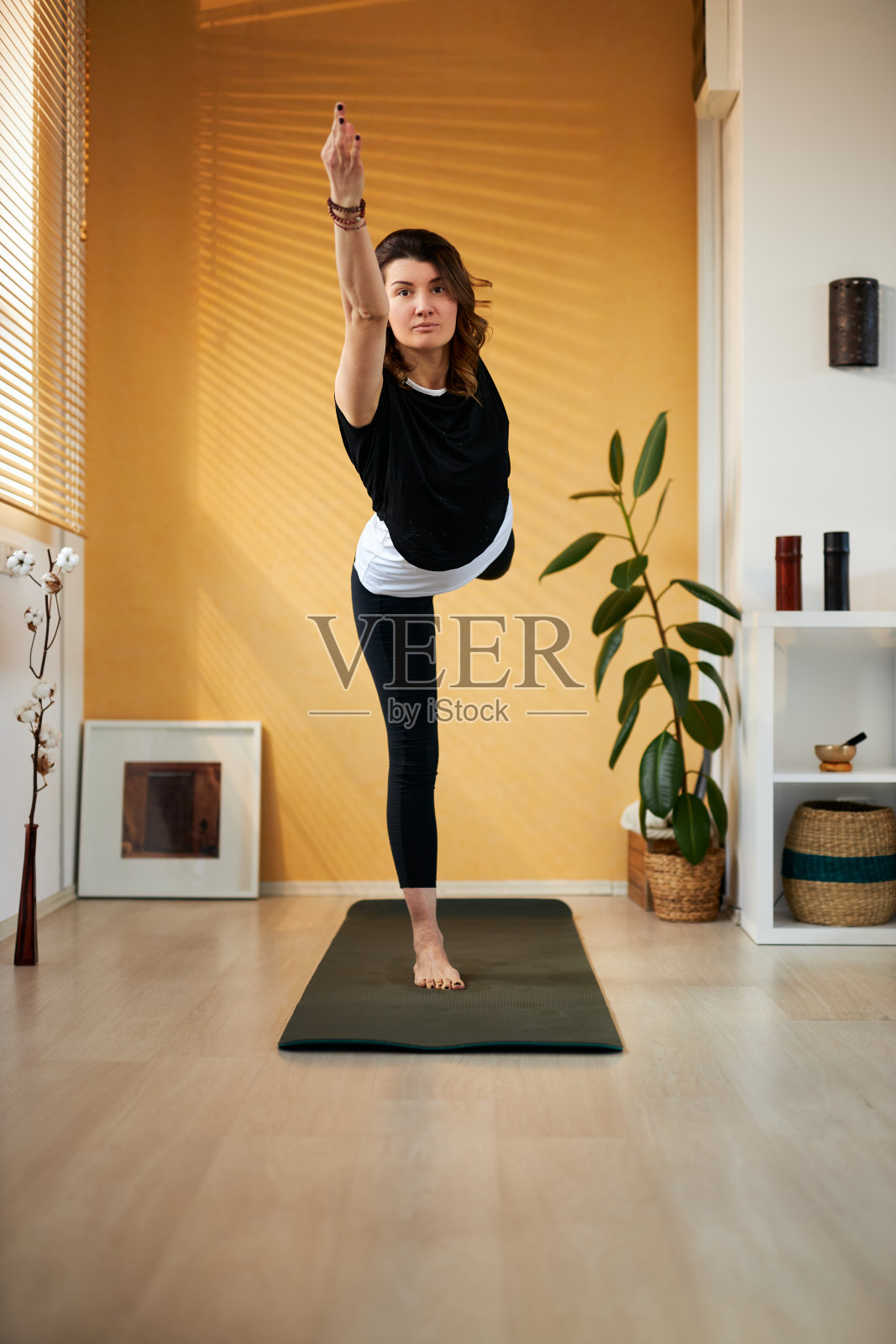 全身苗条的白人瑜伽女性站在一脚在主的舞蹈位置和平衡。室内，早上。照片摄影图片