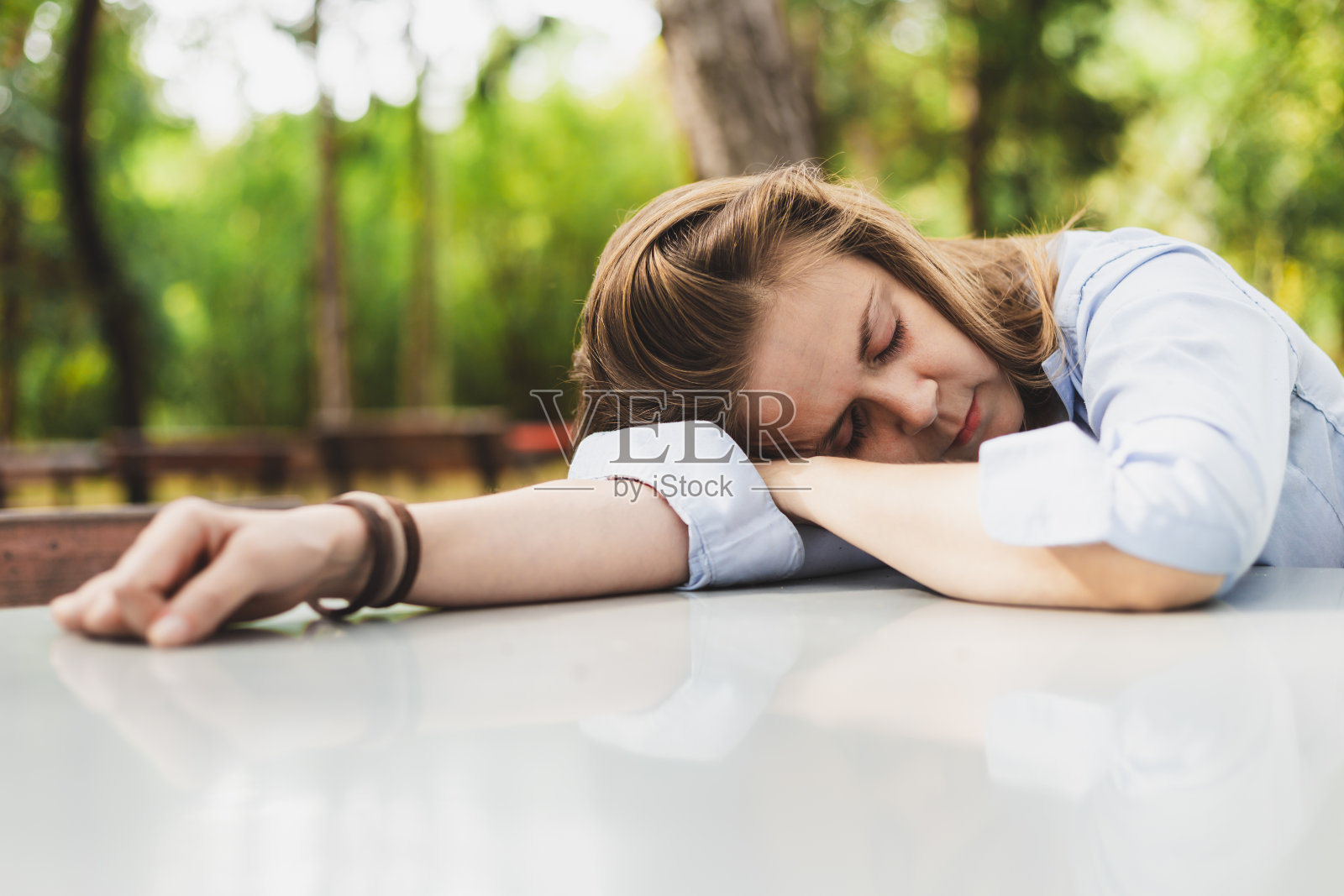 一个女人一只手睡在外面的桌子上照片摄影图片