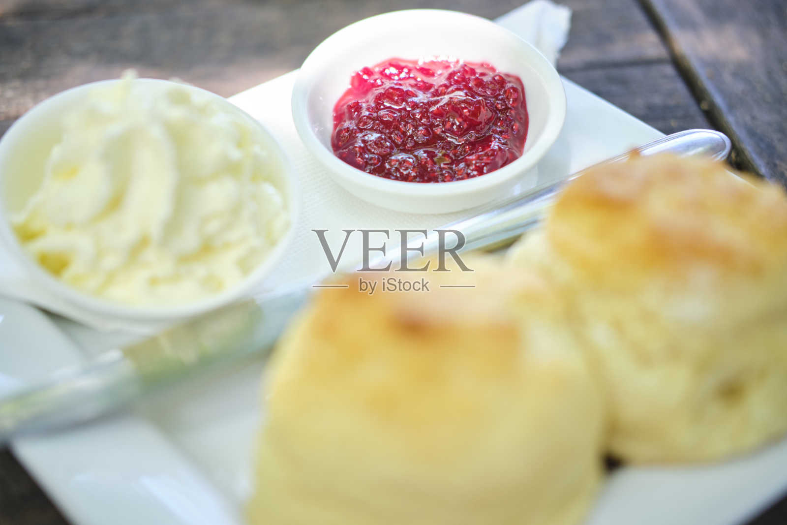 新鲜出炉的烤饼配上果酱和奶油，放在咖啡馆的一张老式桌子上照片摄影图片
