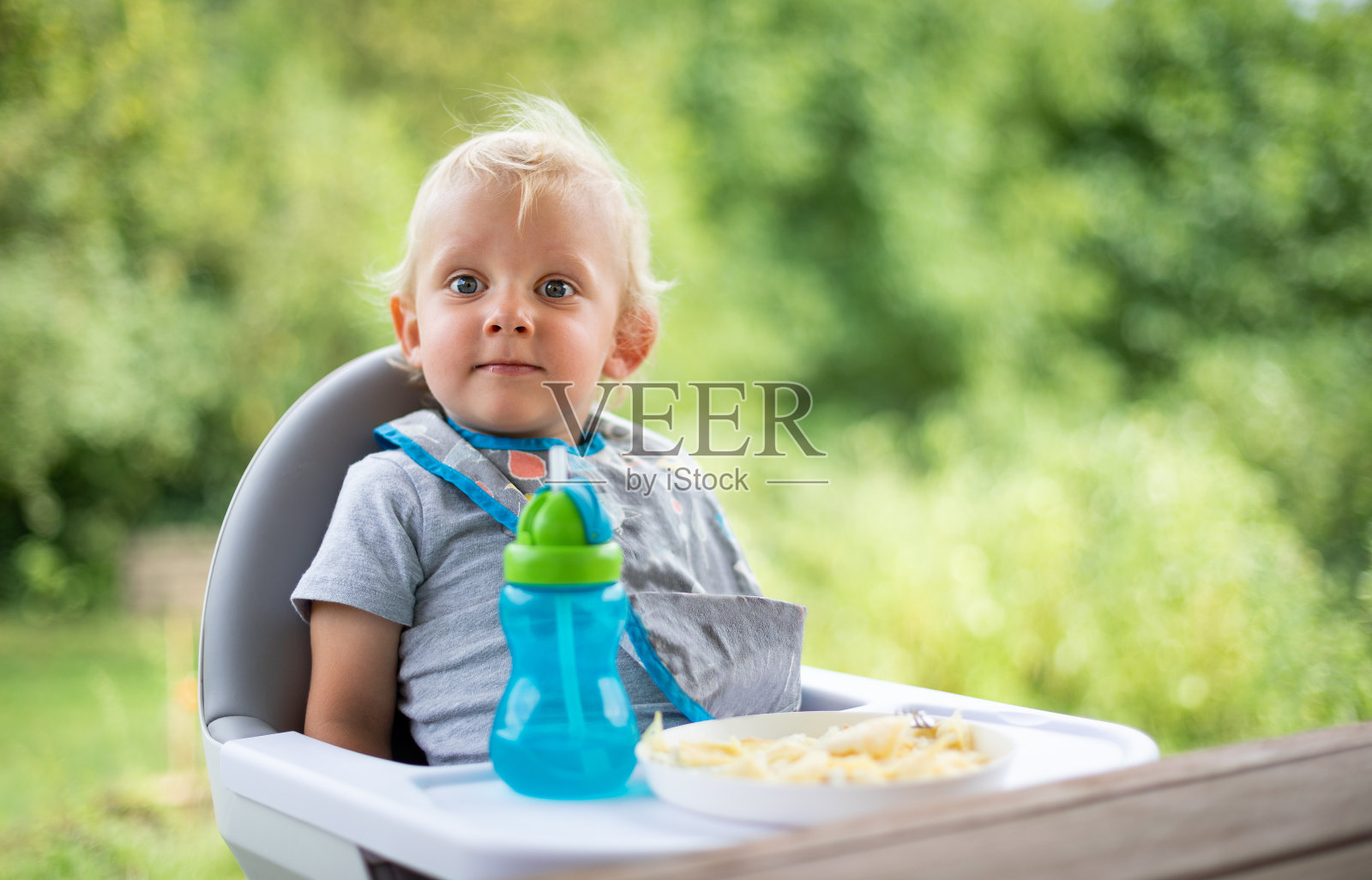 可爱的宝宝坐在户外餐桌旁的高椅子上照片摄影图片