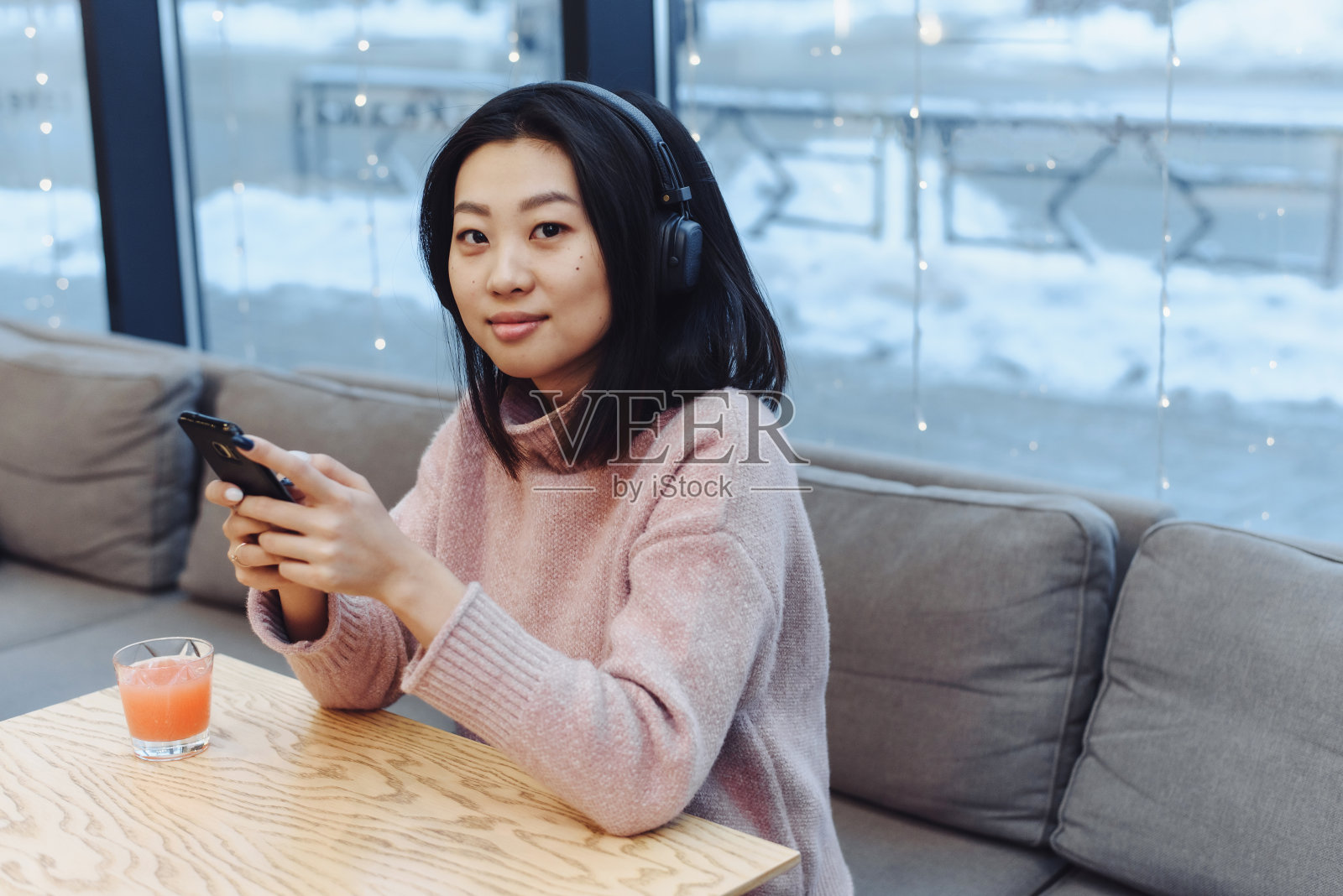 一个亚洲女孩独自坐在咖啡馆里听音乐。在公共场所欣赏音乐照片摄影图片