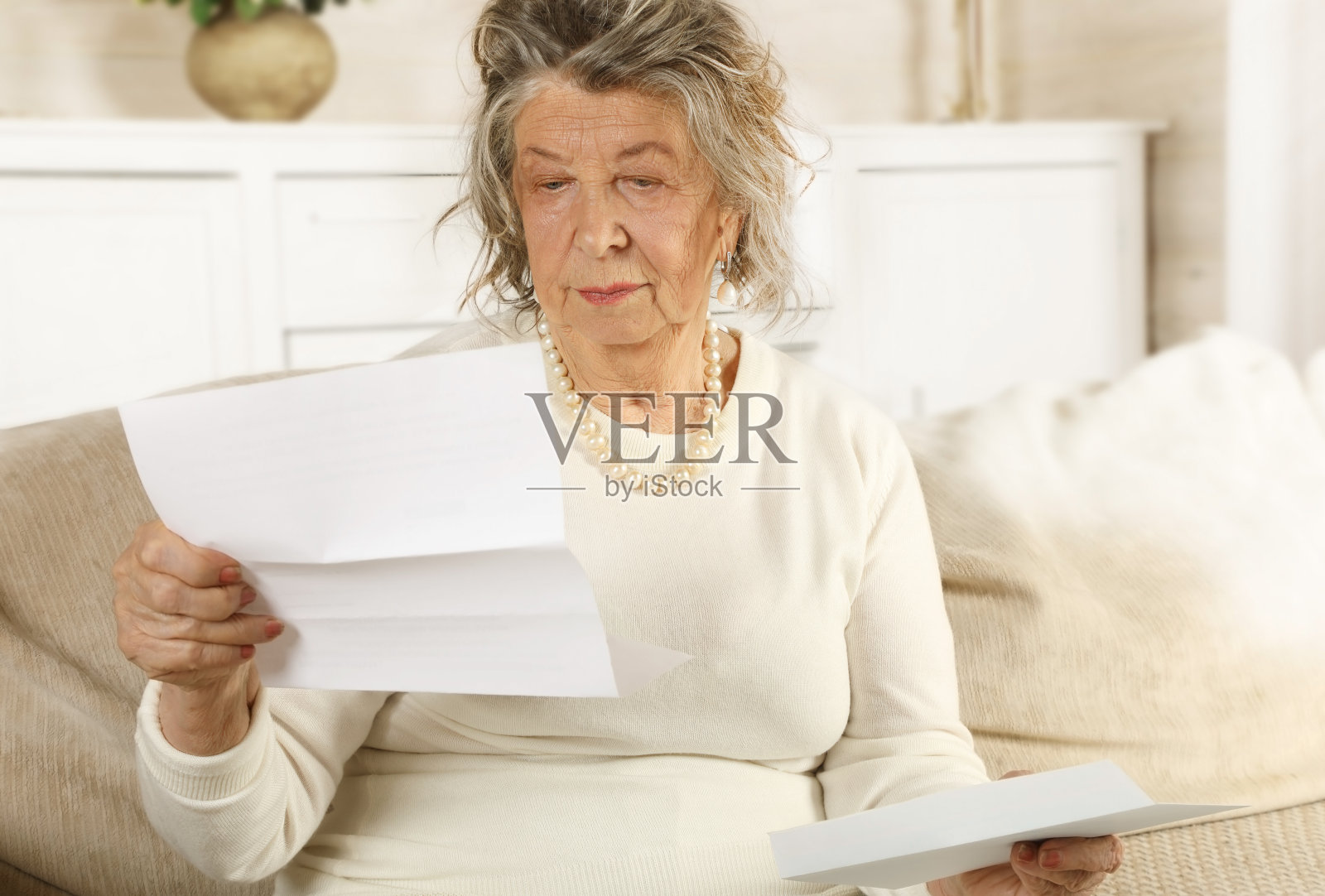 一位老太太坐在沙发上读一封信照片摄影图片