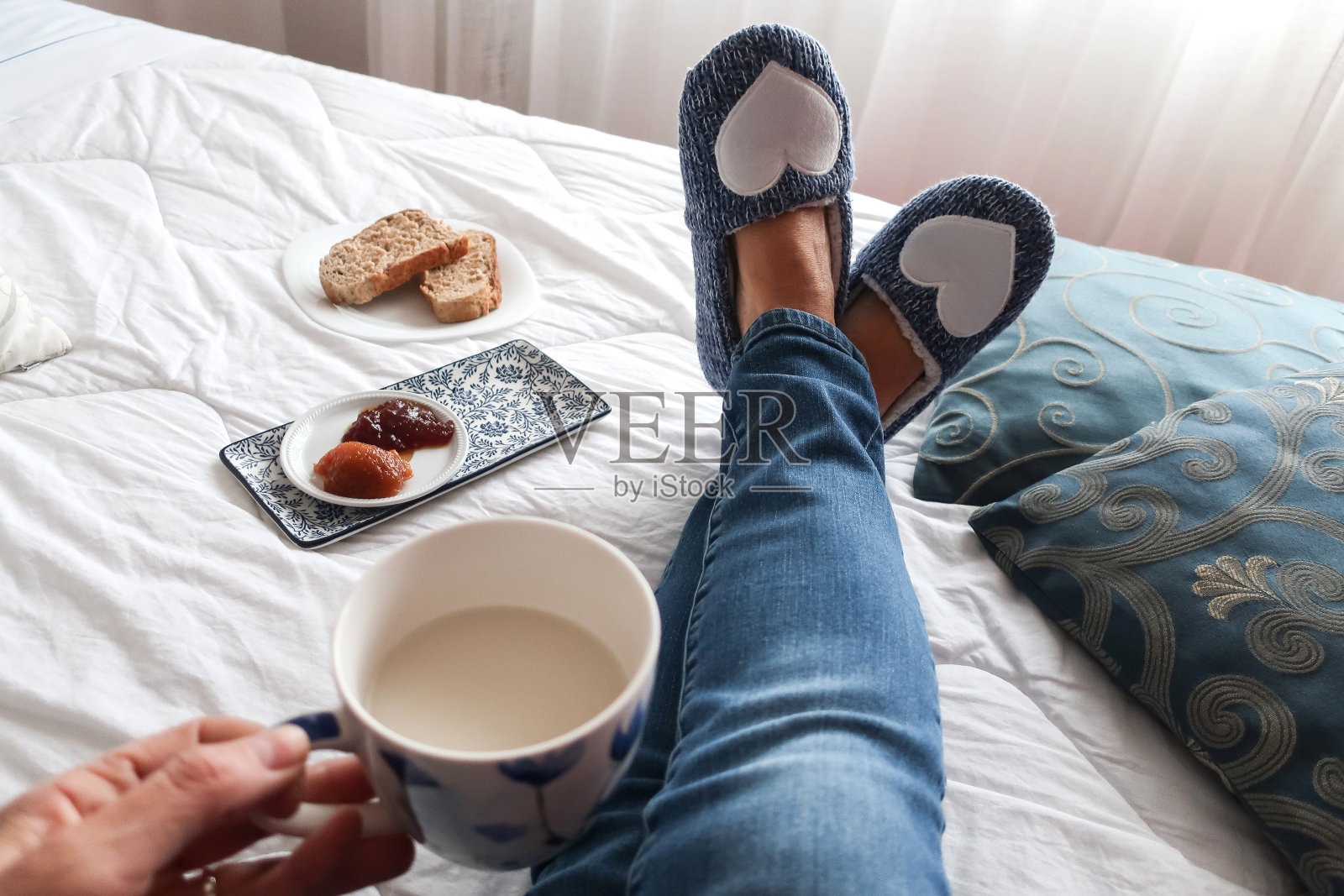 个人观点的高级女人腿放松在床上与蓝色拖鞋在下午茶休息照片摄影图片