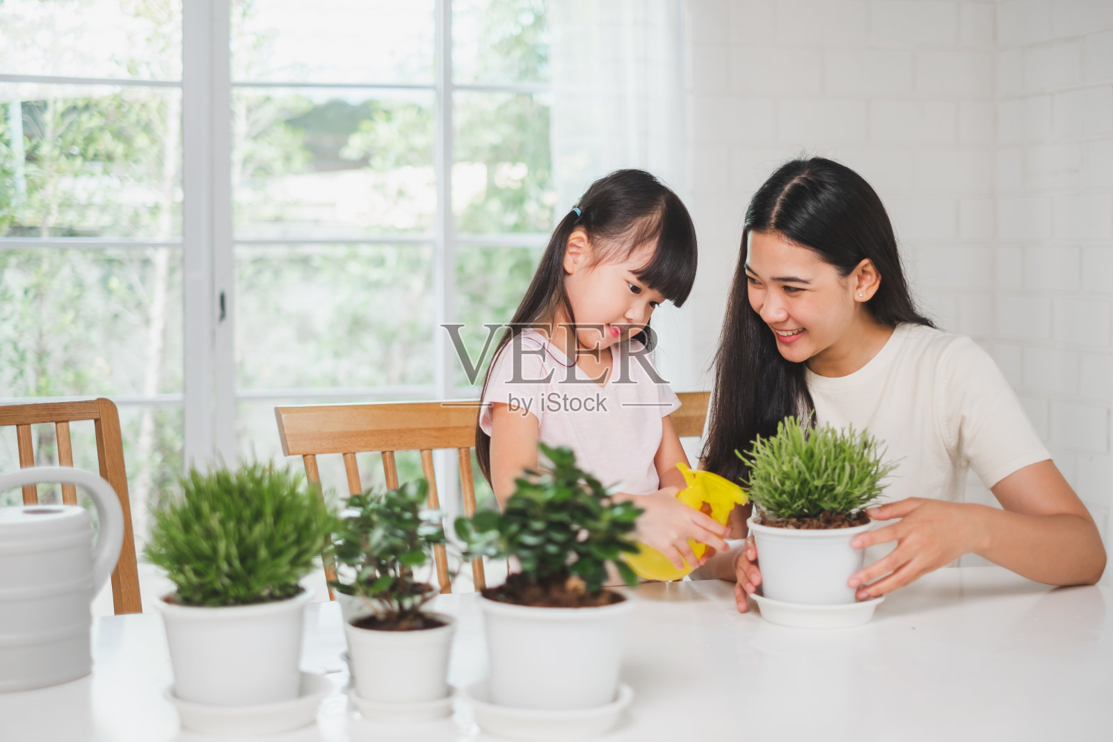 亚洲可爱女孩帮妈妈种花，在家浇水，亚洲家庭家庭园艺理念照片摄影图片