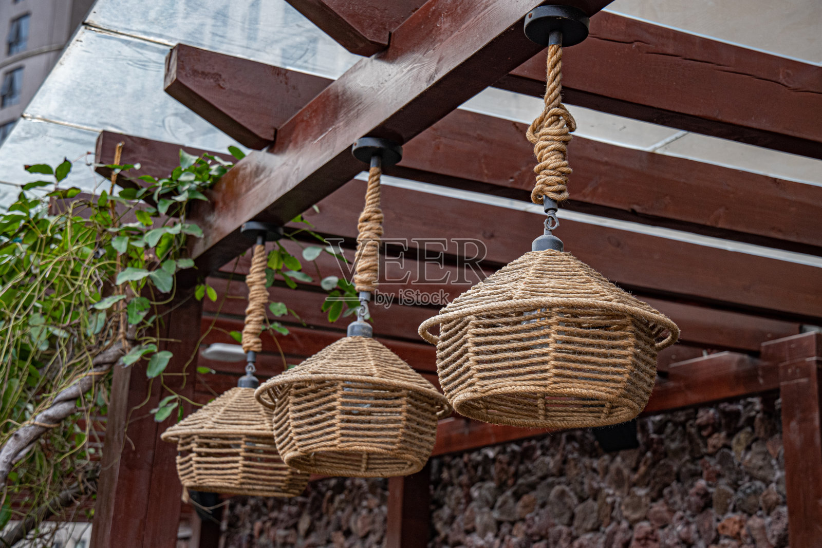 传统的中国编织吊灯悬挂在木制屋顶上。手工制作的柳条缠绕灯，环保风格。亚洲户外照明装饰。照片摄影图片
