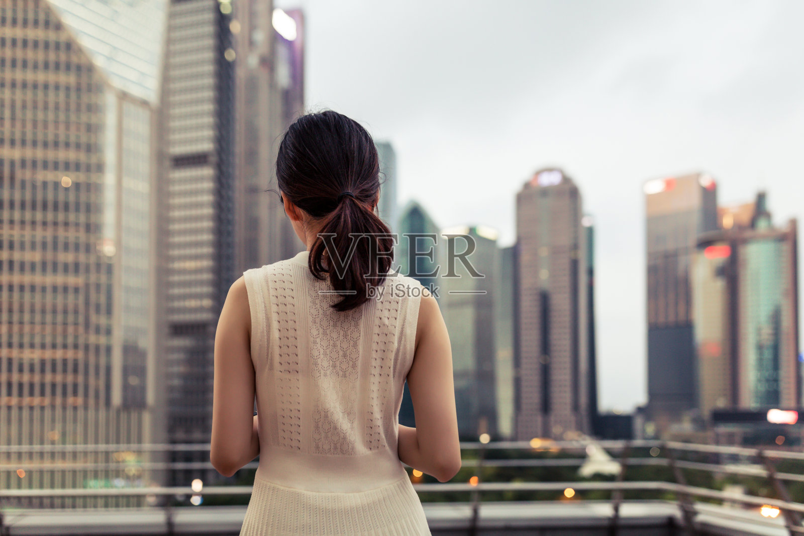 亚洲年轻女商人望着金融摩天大楼。照片摄影图片