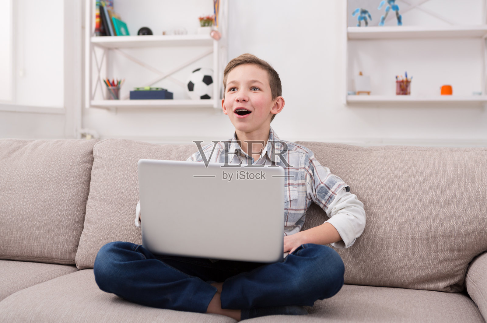 十几岁的男孩在家里的沙发上用笔记本电脑照片摄影图片