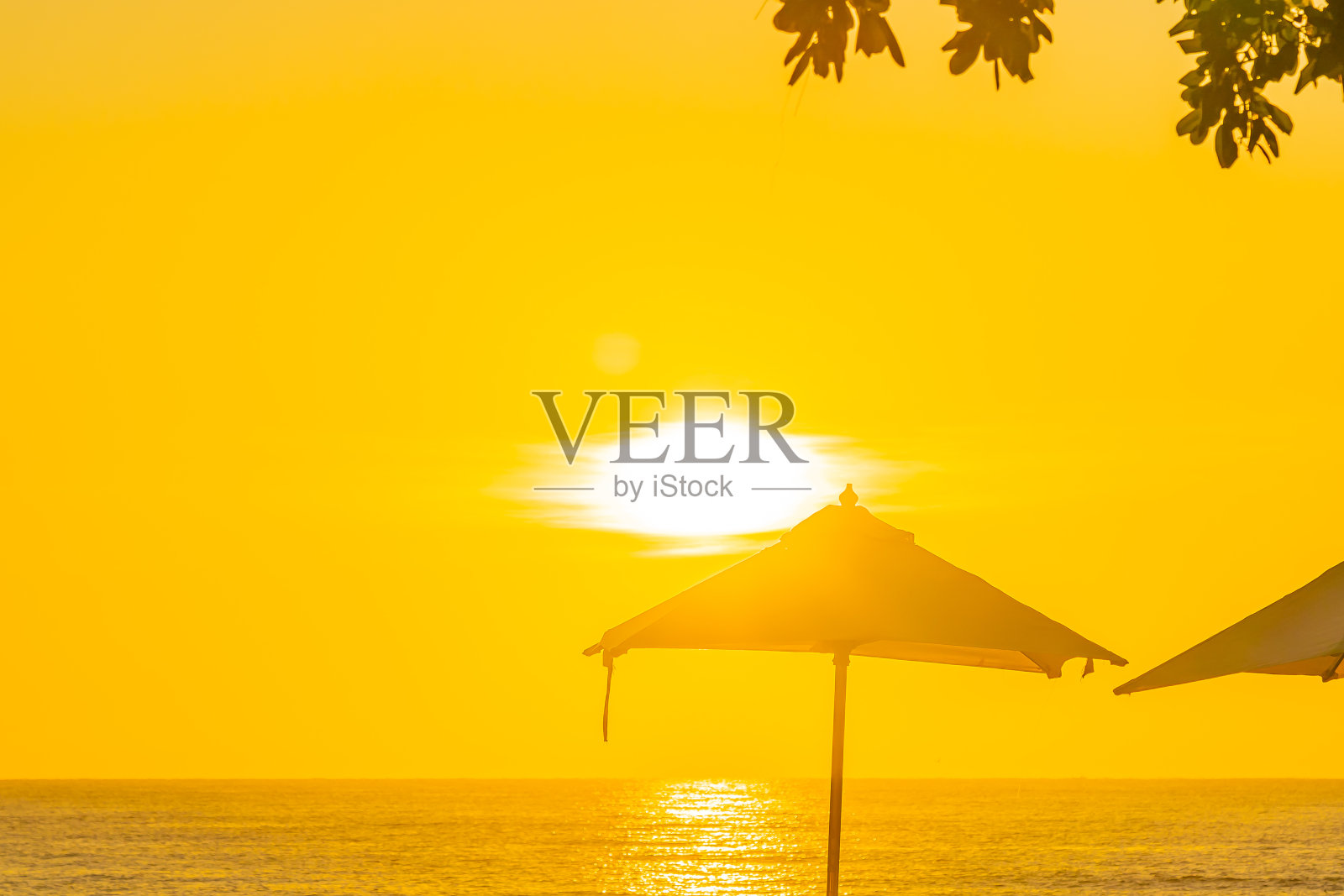 美丽的热带户外海滩、海洋、遮阳伞和椅子在户外游泳池周围日落或日出时间照片摄影图片