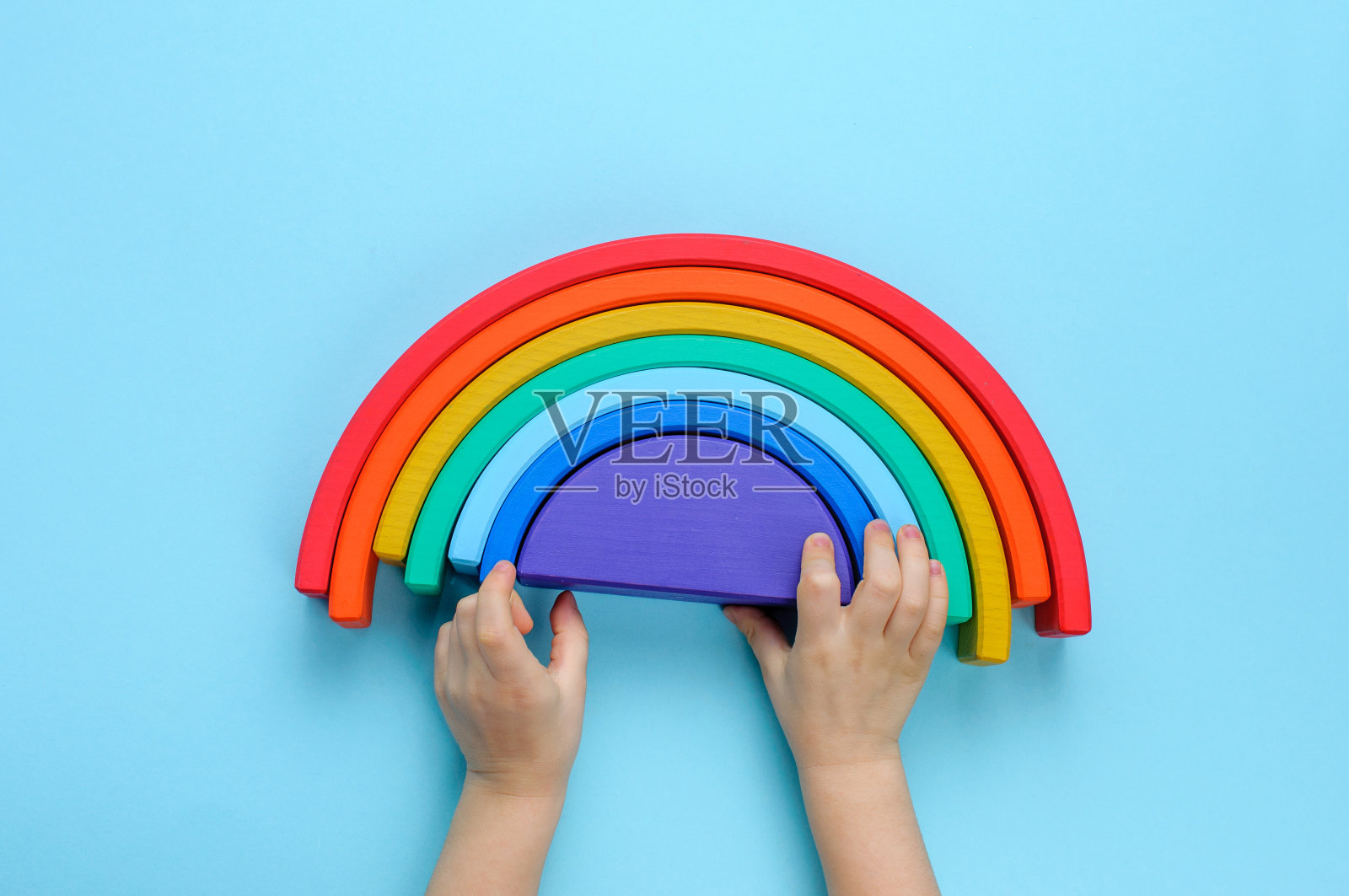 孩子的手玩木制玩具彩虹在蓝色的背景照片摄影图片