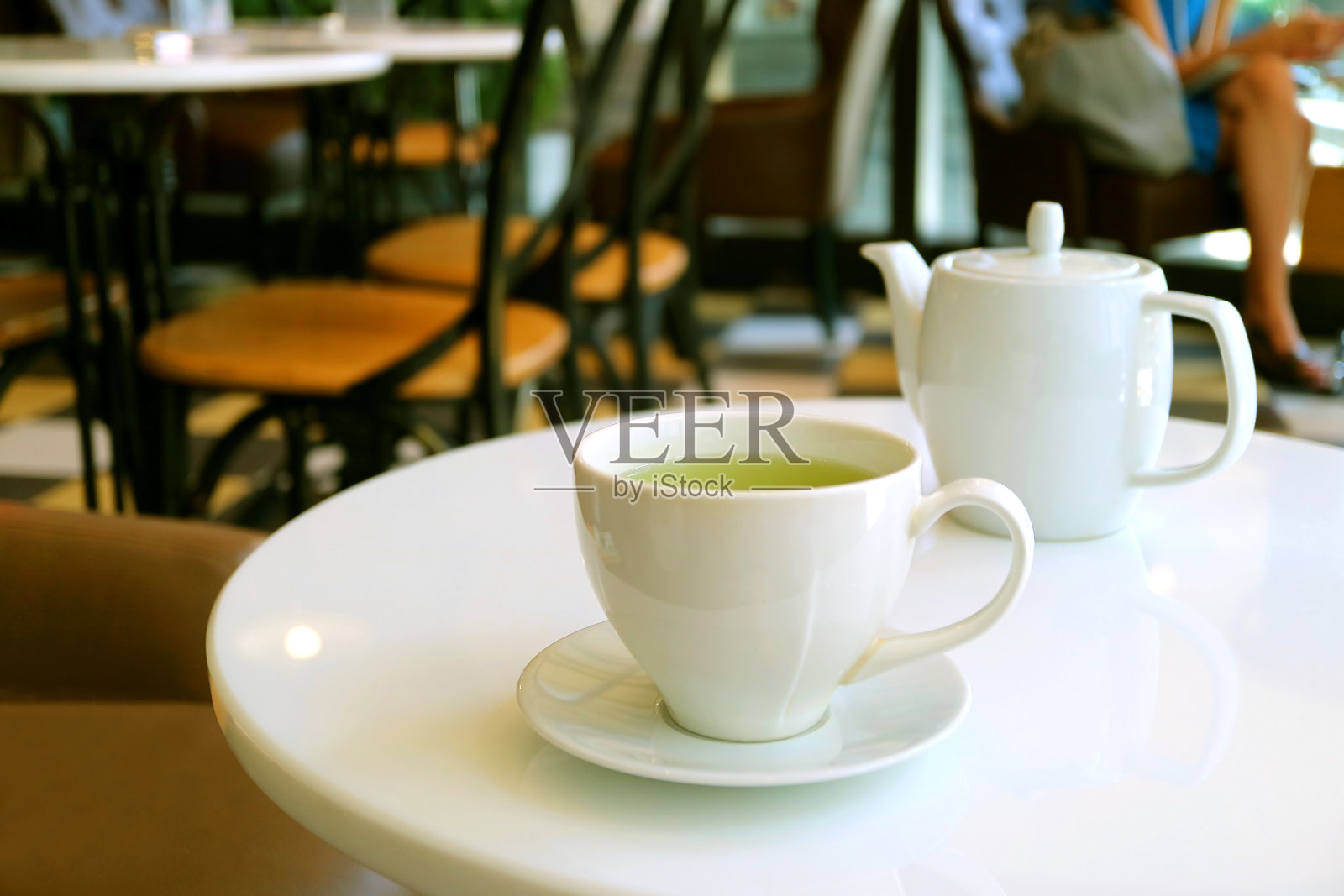 特写一杯绿茶和茶壶在茶室的白色圆桌上照片摄影图片