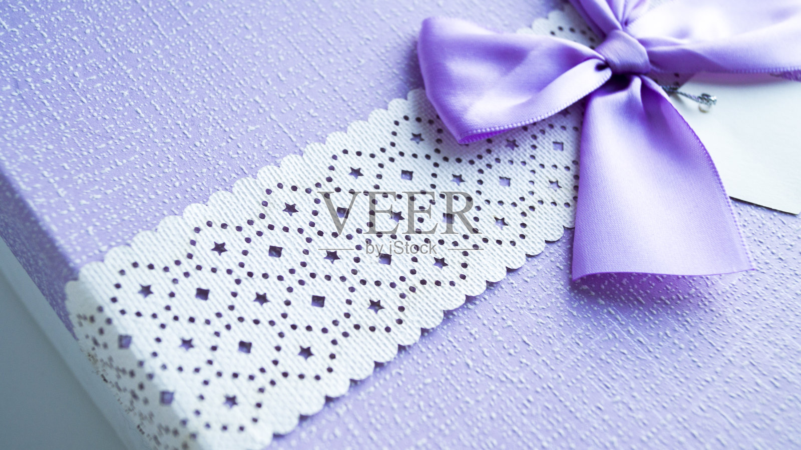 特写通过白色丝带上的图案与紫色礼盒和紫色蝴蝶结。照片摄影图片